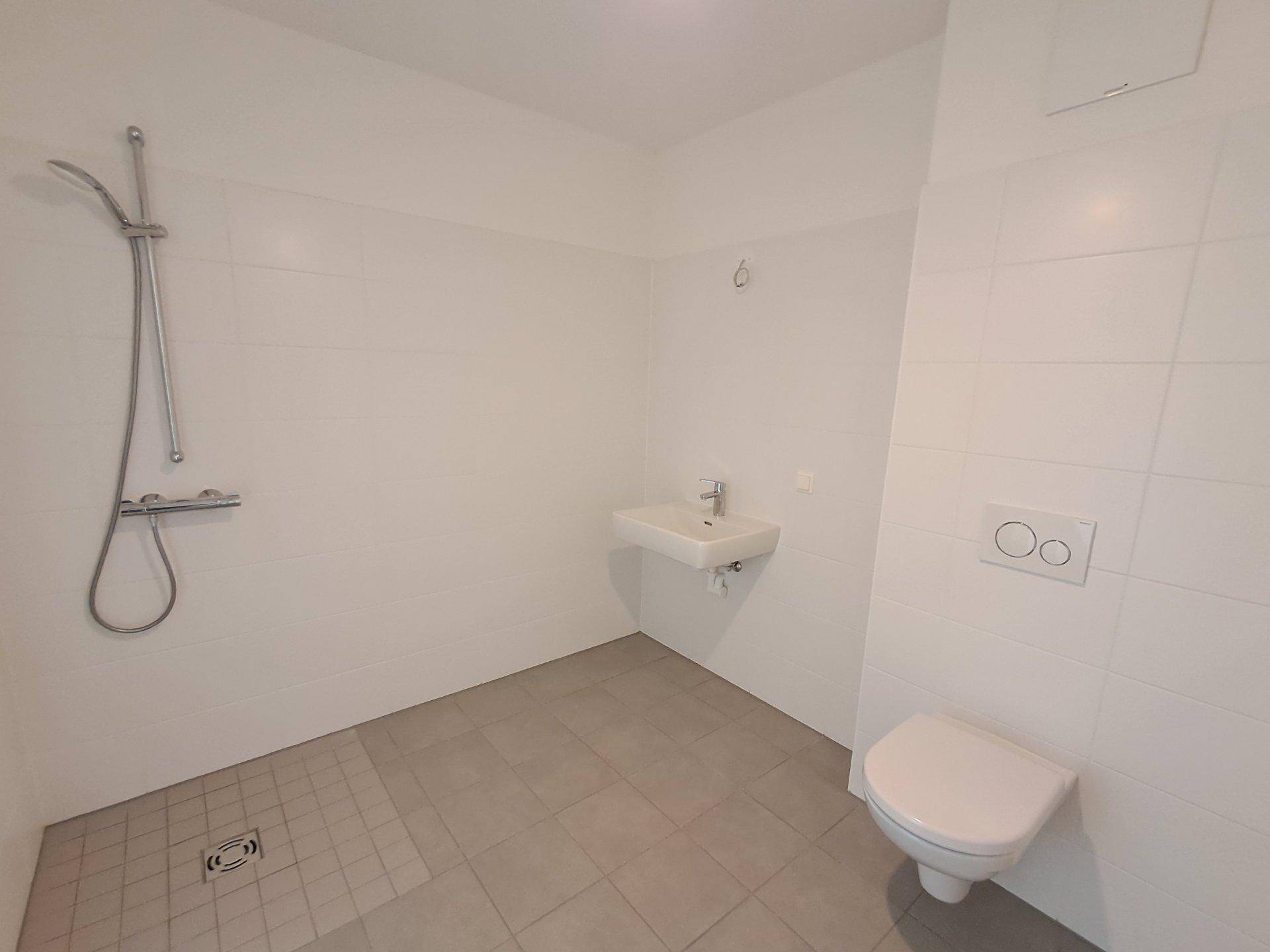 Helles Badezimmer mit ebenerdiger Dusche und Wand-WC, bereit für die Einrichtung.