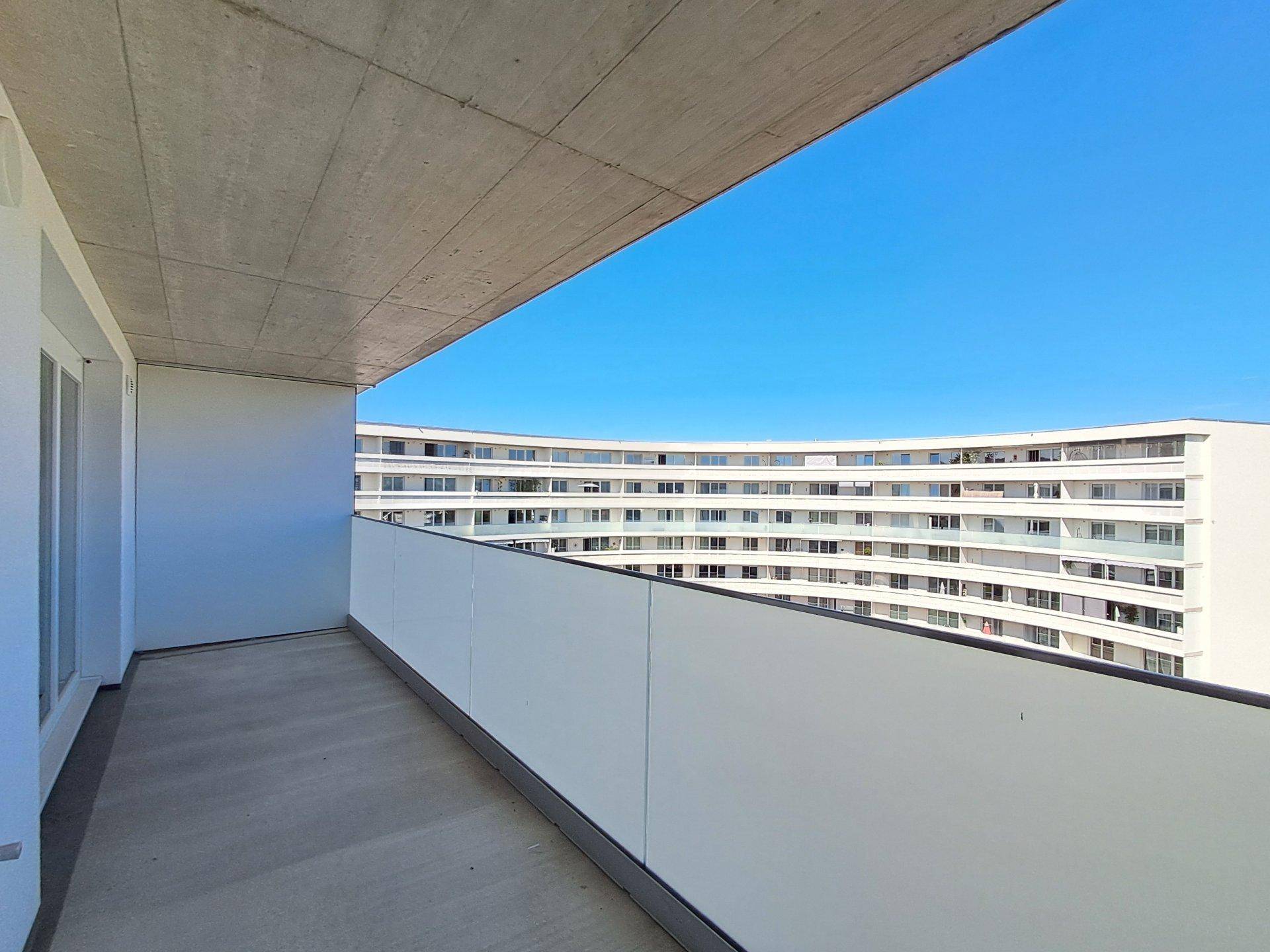 Heller Balkon mit Blick auf moderne Wohngebäude und die umliegende Architektur.