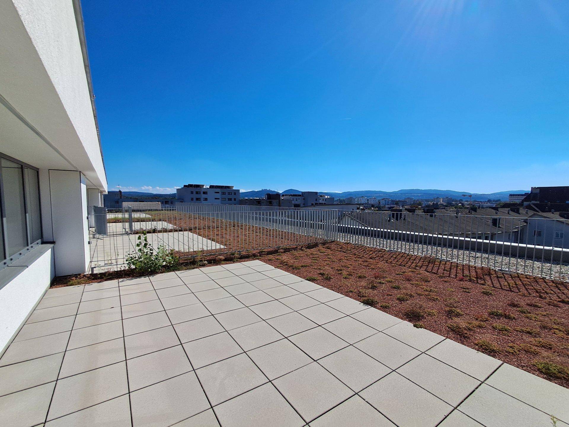 Weitläufige Dachterrasse mit gepflastertem Bereich und Panoramablick auf die Umgebung.