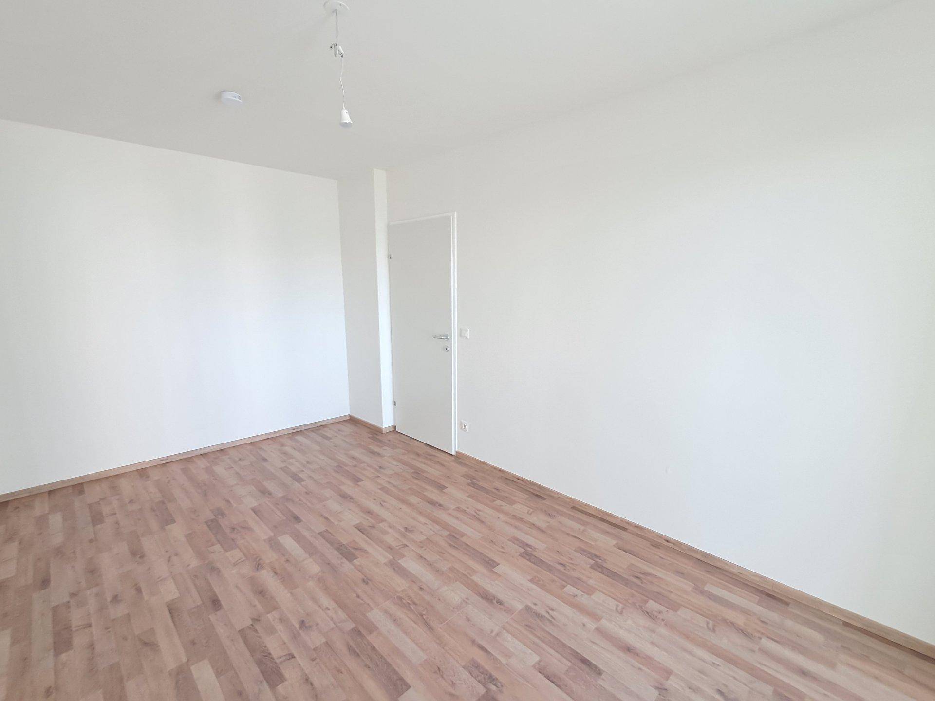 Leeres Schlafzimmer mit Holzboden und weißen Wänden, ideal für individuelle Einrichtung.