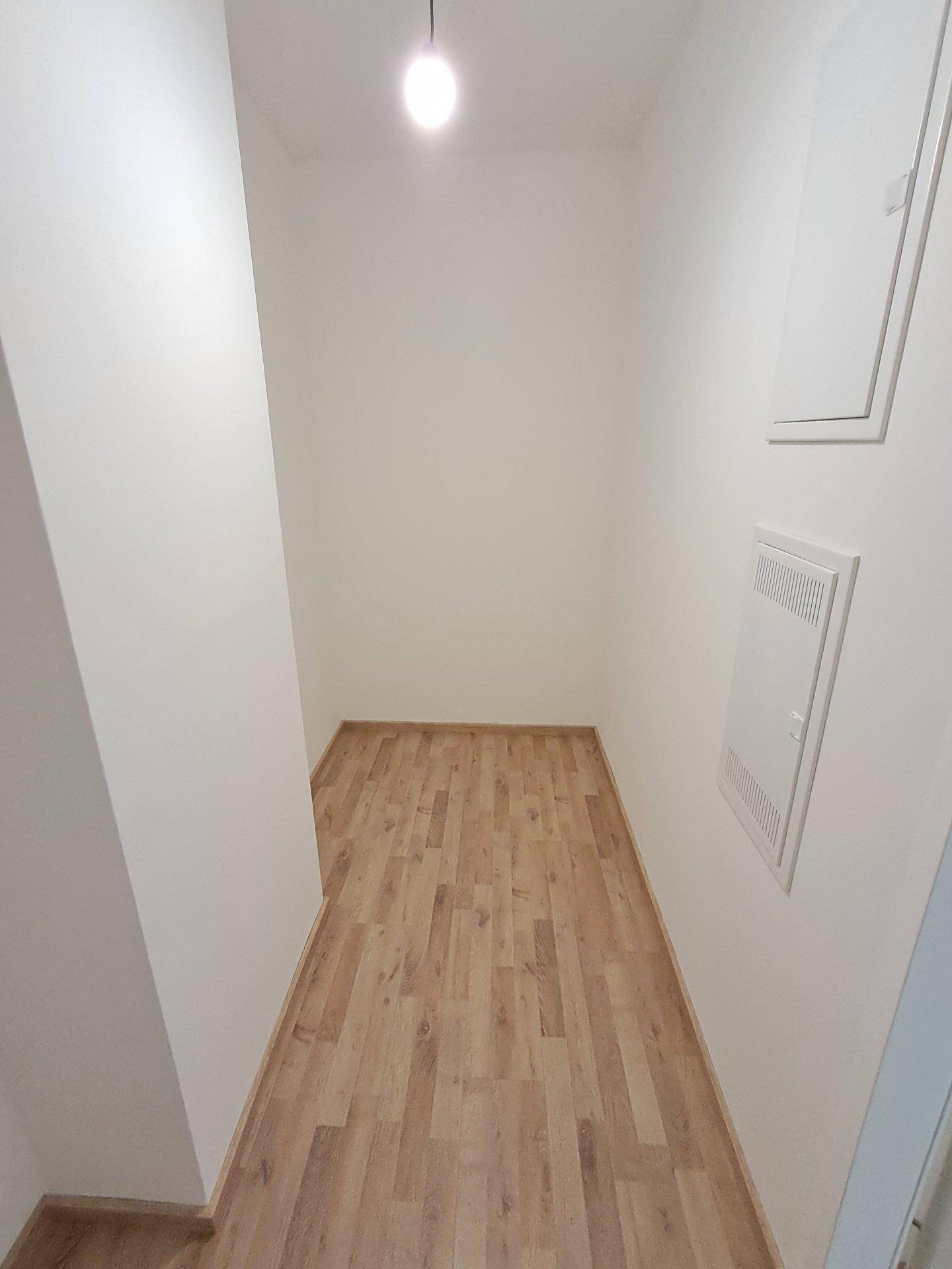 Schmaler Abstellraum mit Laminatboden und weißen Wänden, ideal für zusätzlichen Stauraum.