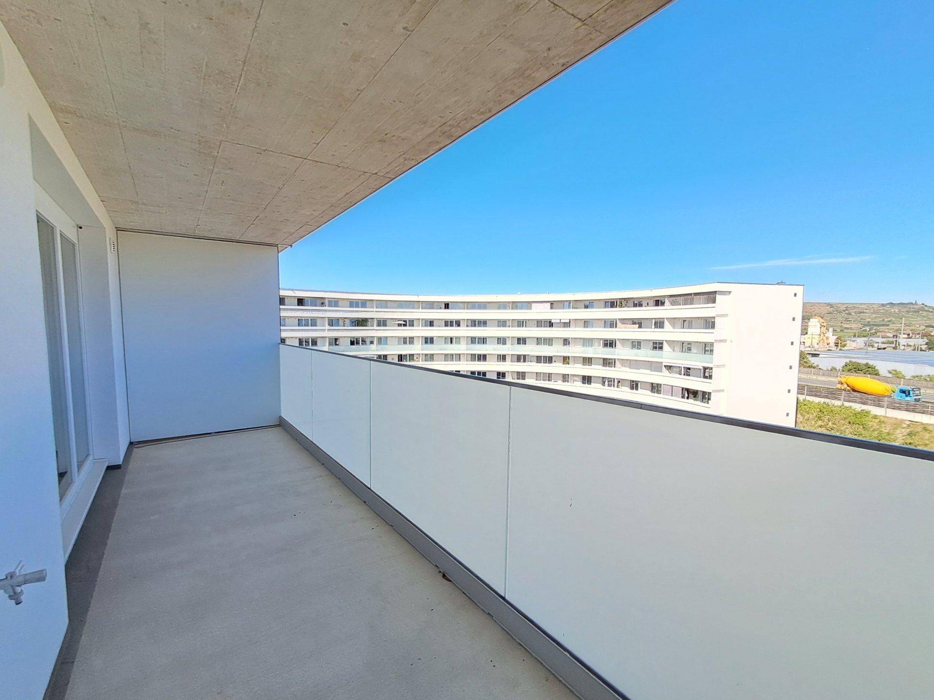 Heller Balkon mit moderner Brüstung und Blick auf die umliegende Bebauung.