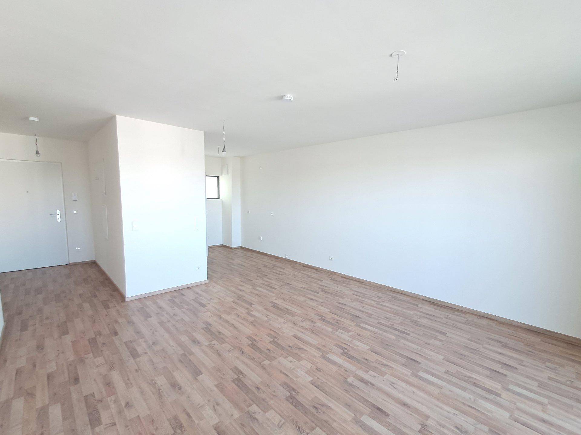 Geräumiger, unmöblierter Raum mit Holzfußboden und viel Tageslicht.