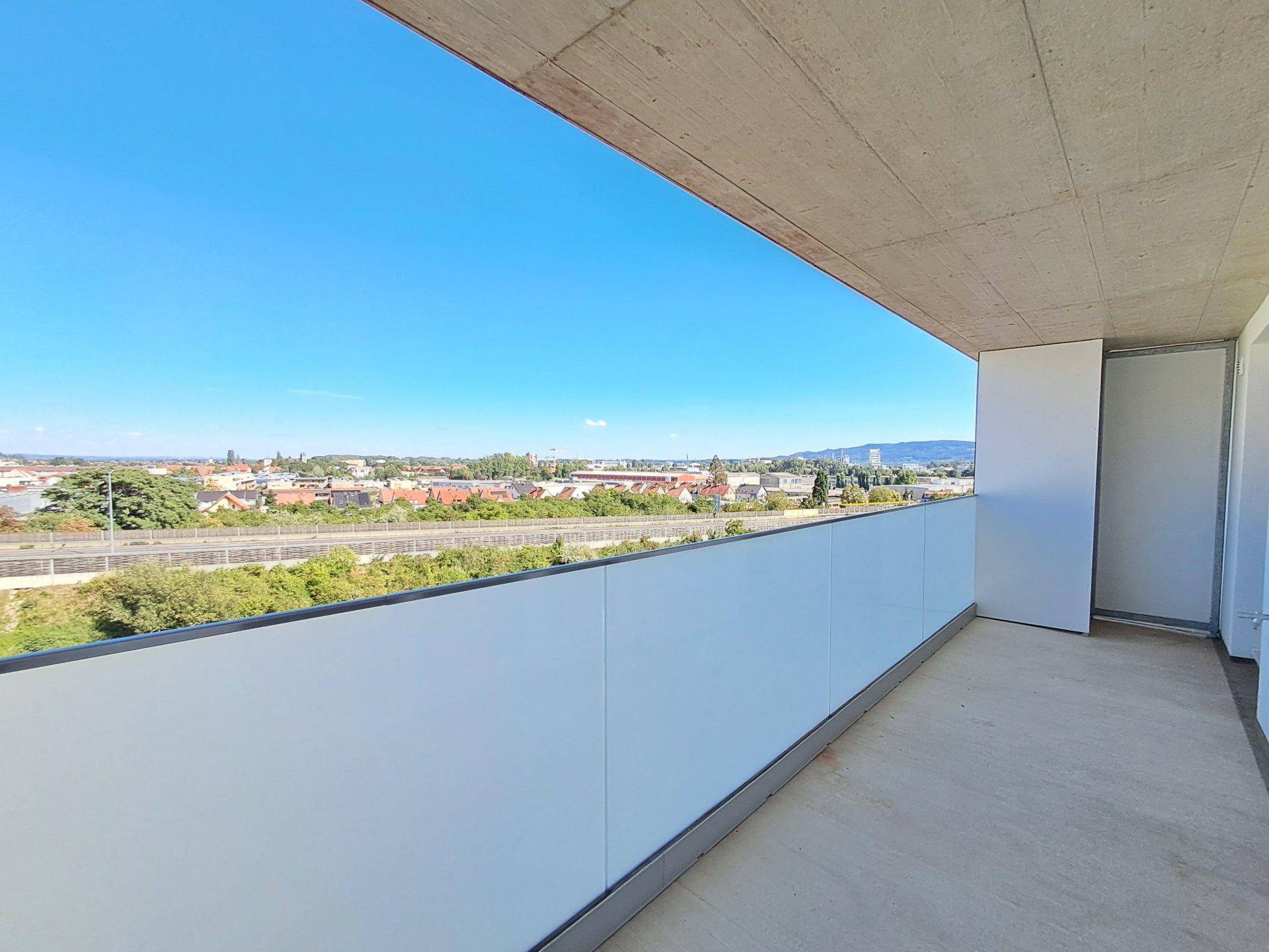 Geräumiger Balkon mit weitem Stadtblick und viel Tageslicht.