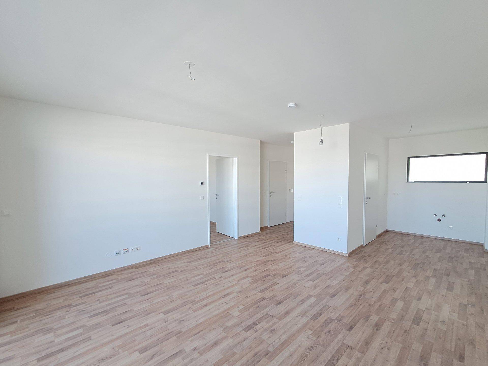 Heller, leerer Wohnbereich mit Holzboden und Fenster, bereit zur individuellen Gestaltung.