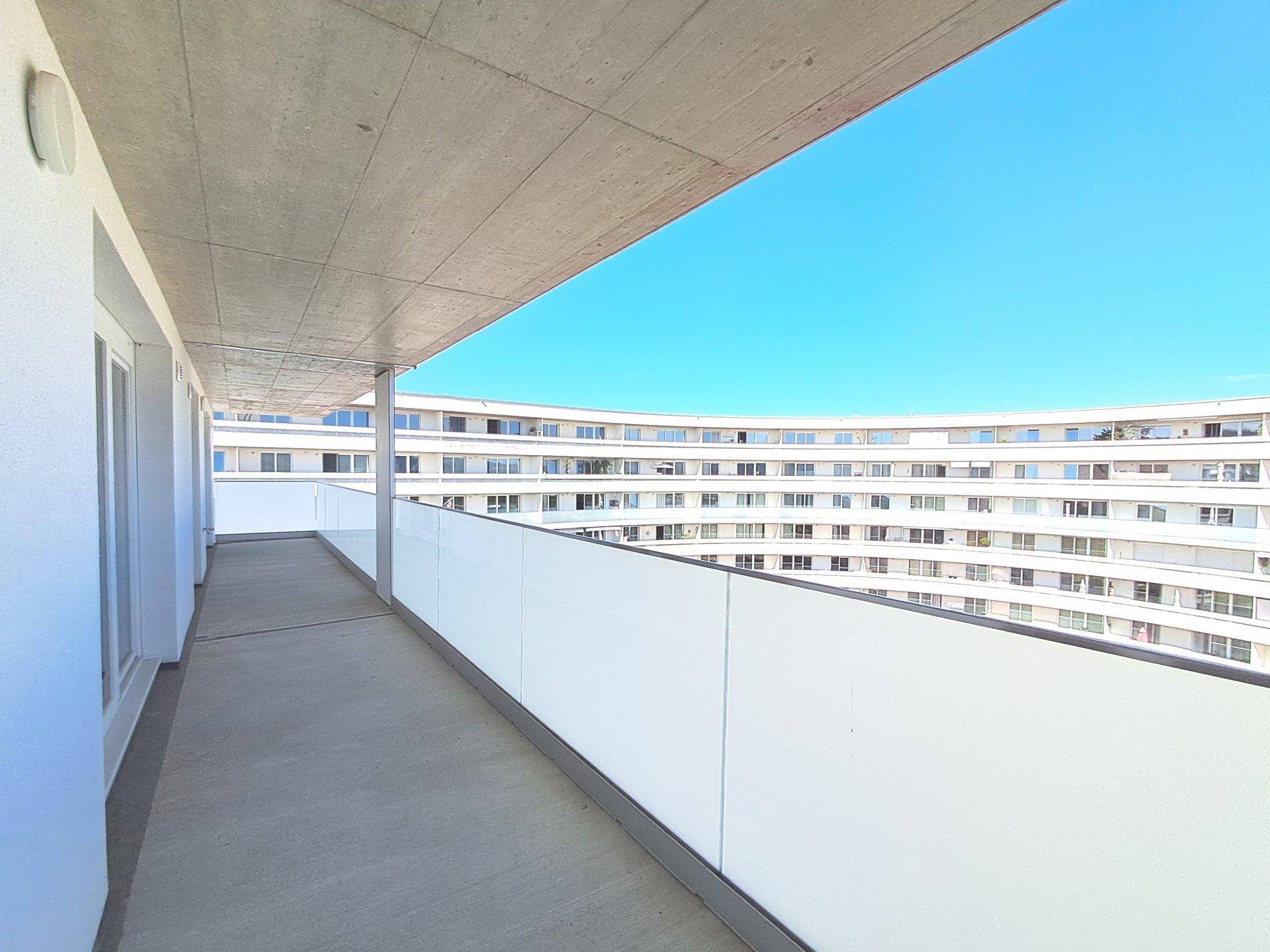Geräumiger Balkon mit Blick auf die moderne Architektur des gegenüberliegenden Gebäudes.
