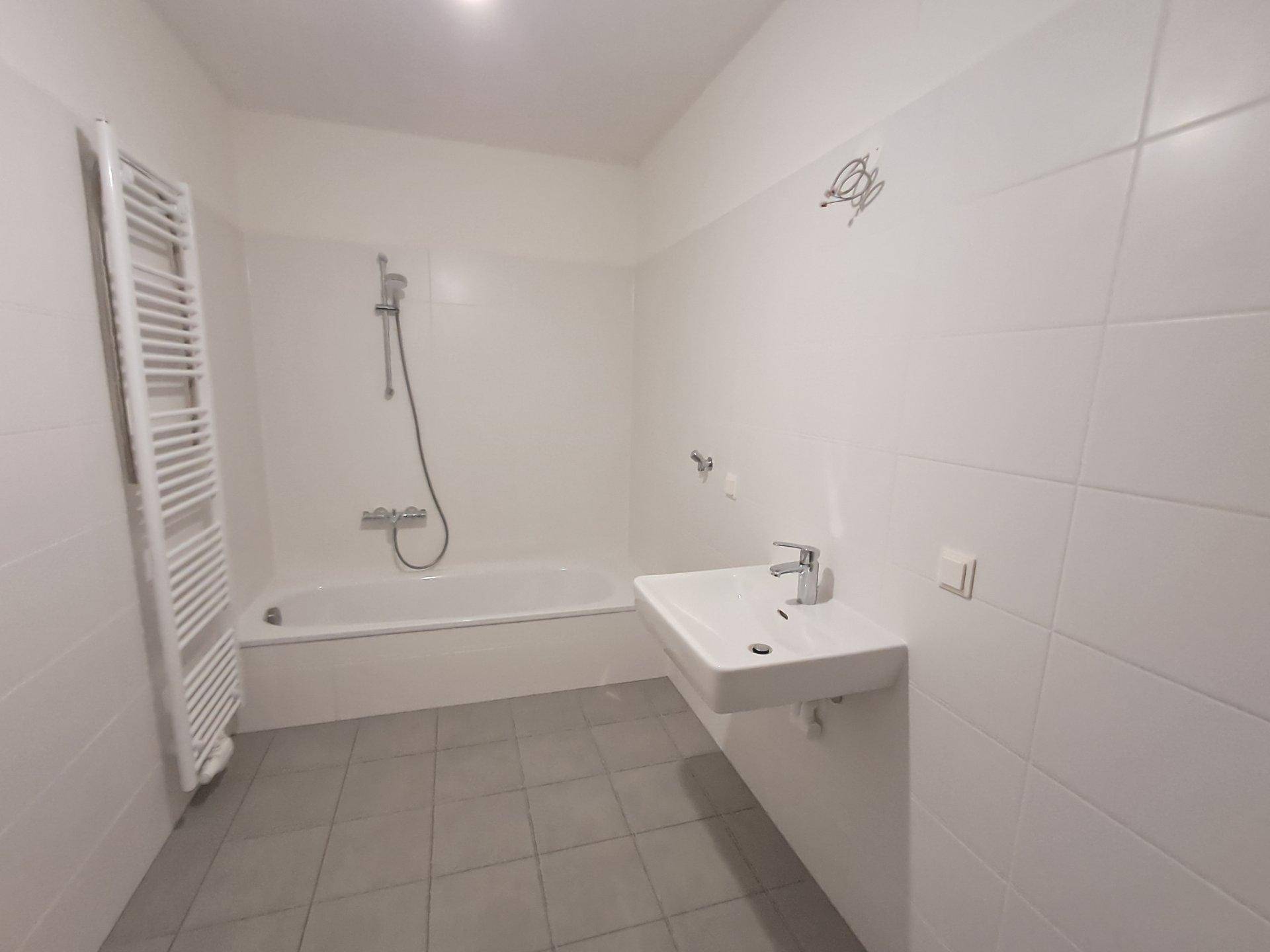 Helles Badezimmer mit Badewanne, Dusche, Waschbecken und beheiztem Handtuchhalter.