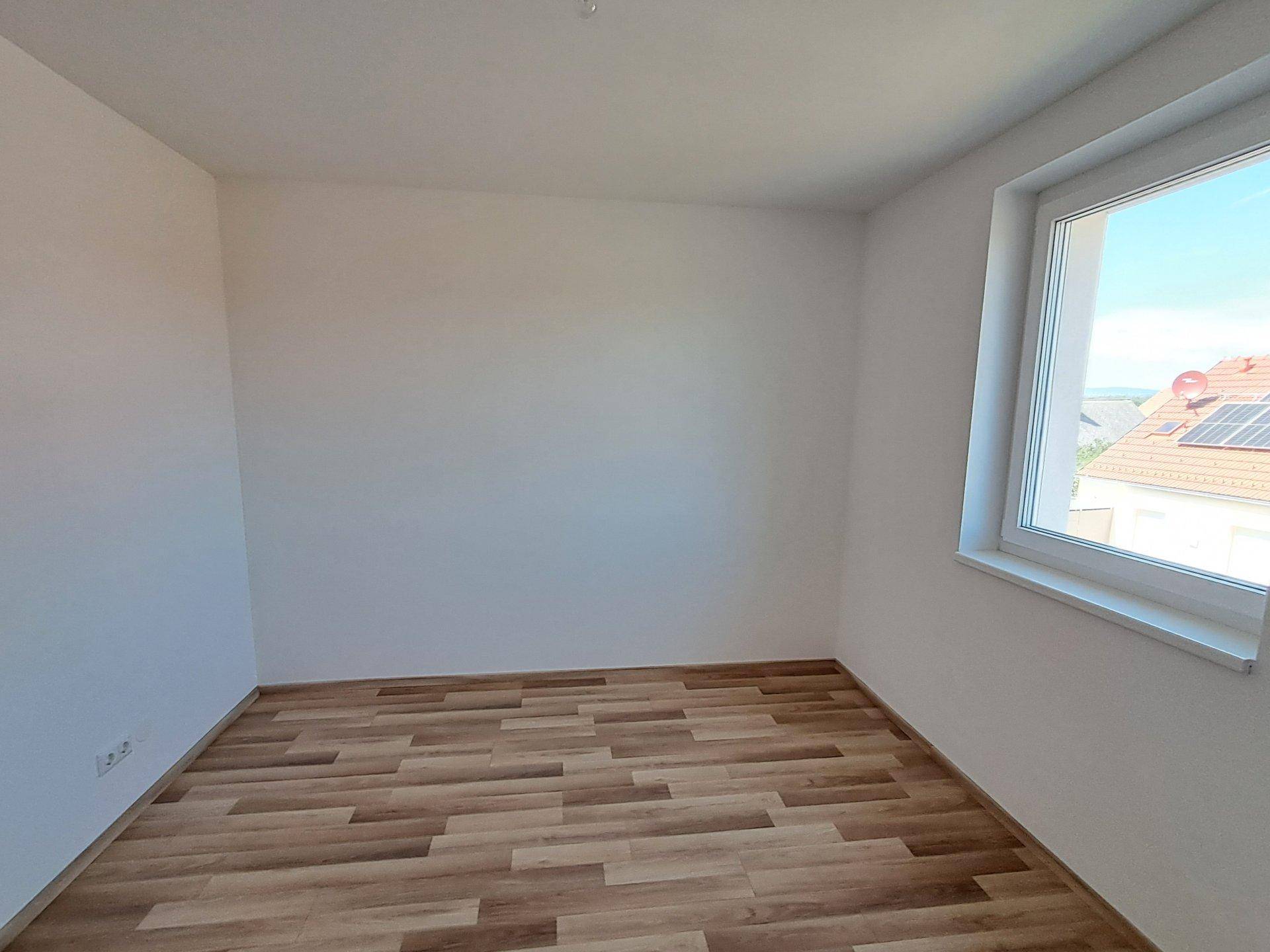 Unmöbliertes Zimmer mit Holzfußboden und einem Fenster, bietet vielseitige Nutzungsmöglichkeiten.