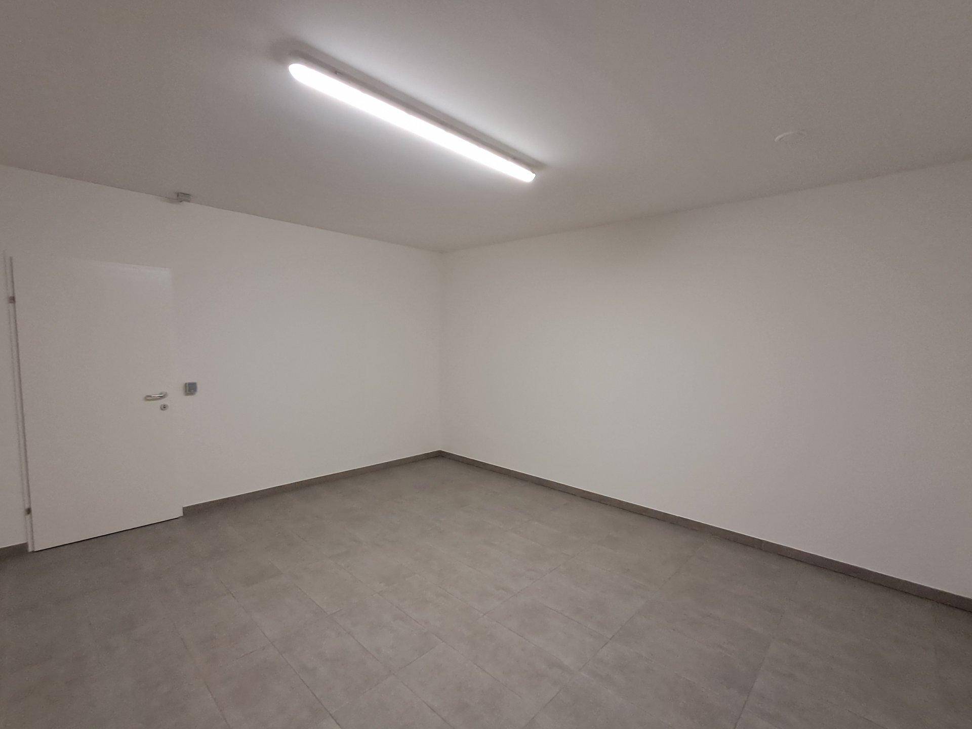 Leerer Raum mit grauen Fliesen und einer weißen Tür, vielseitig nutzbar.