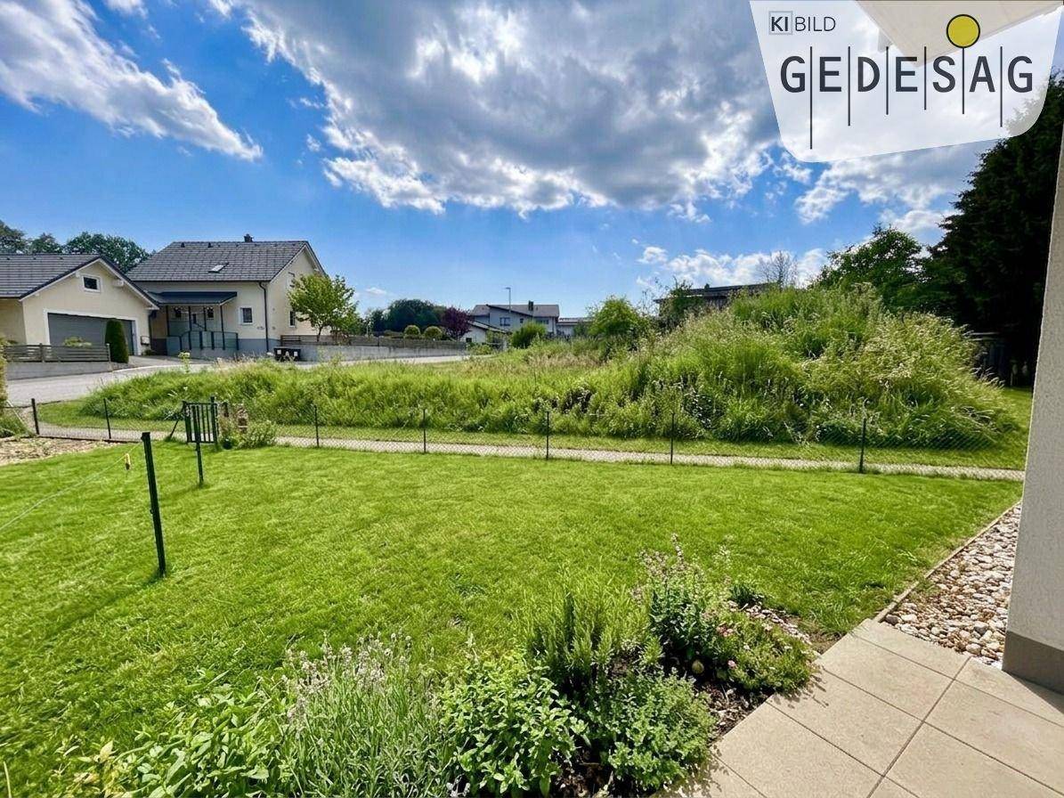 Gepflegter Gartenbereich mit Rasenfläche und Blick auf die umliegende Wohnbebauung.