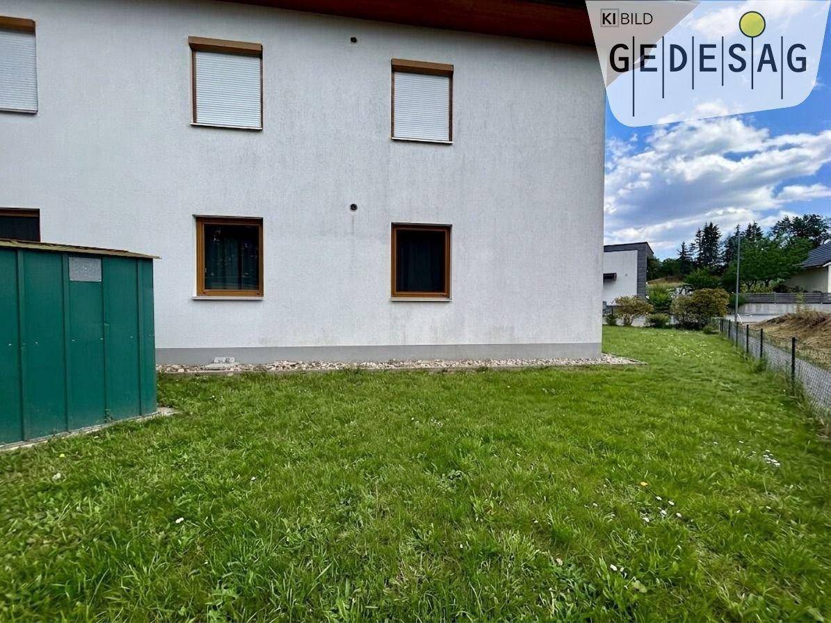 Seitenansicht des Gebäudes mit grünem Garten und einem praktischen Gartenschuppen.