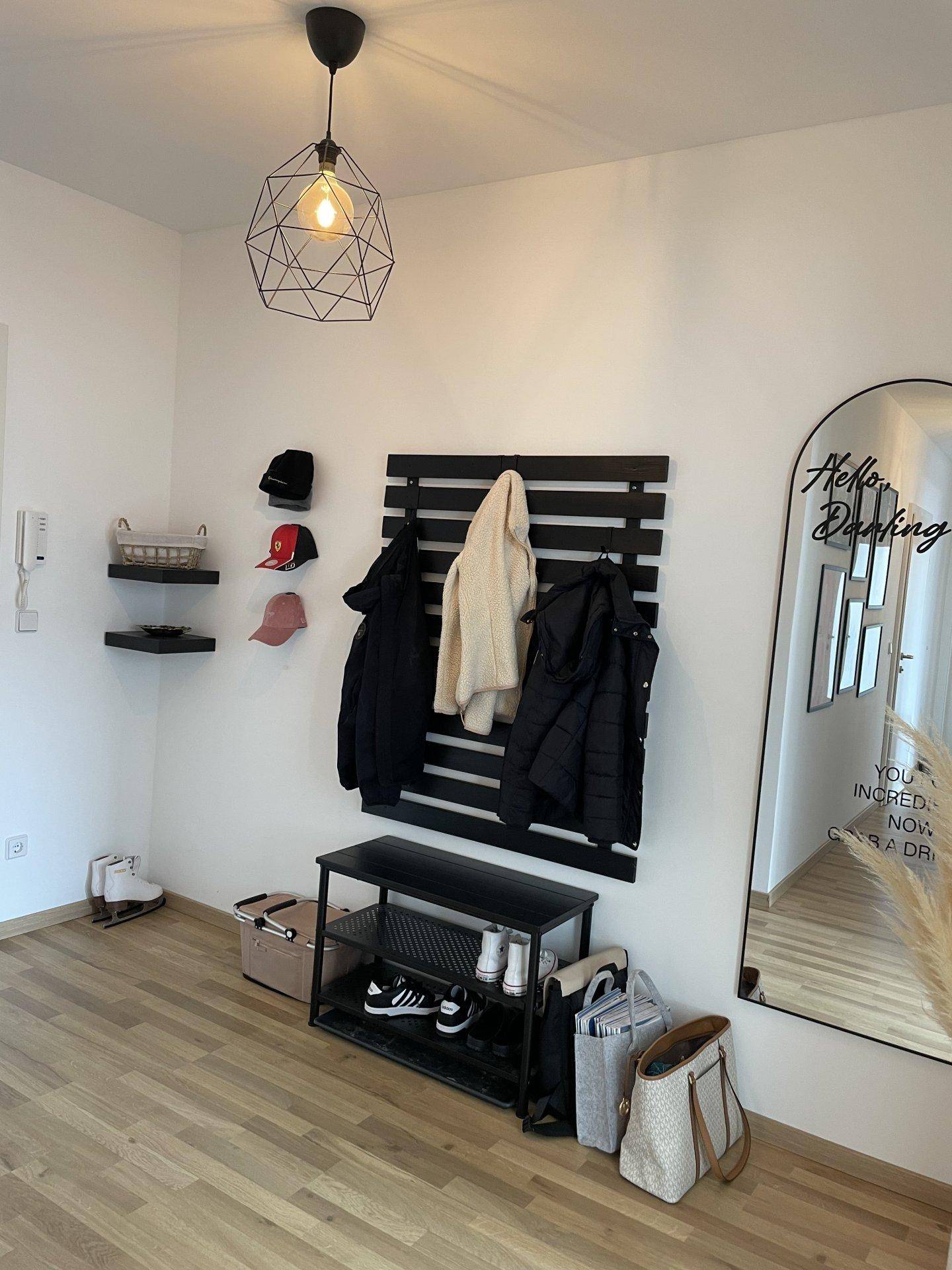 Eingangsbereich mit Garderobe, Schuhregal und großem Spiegel, hell und funktional gestaltet.