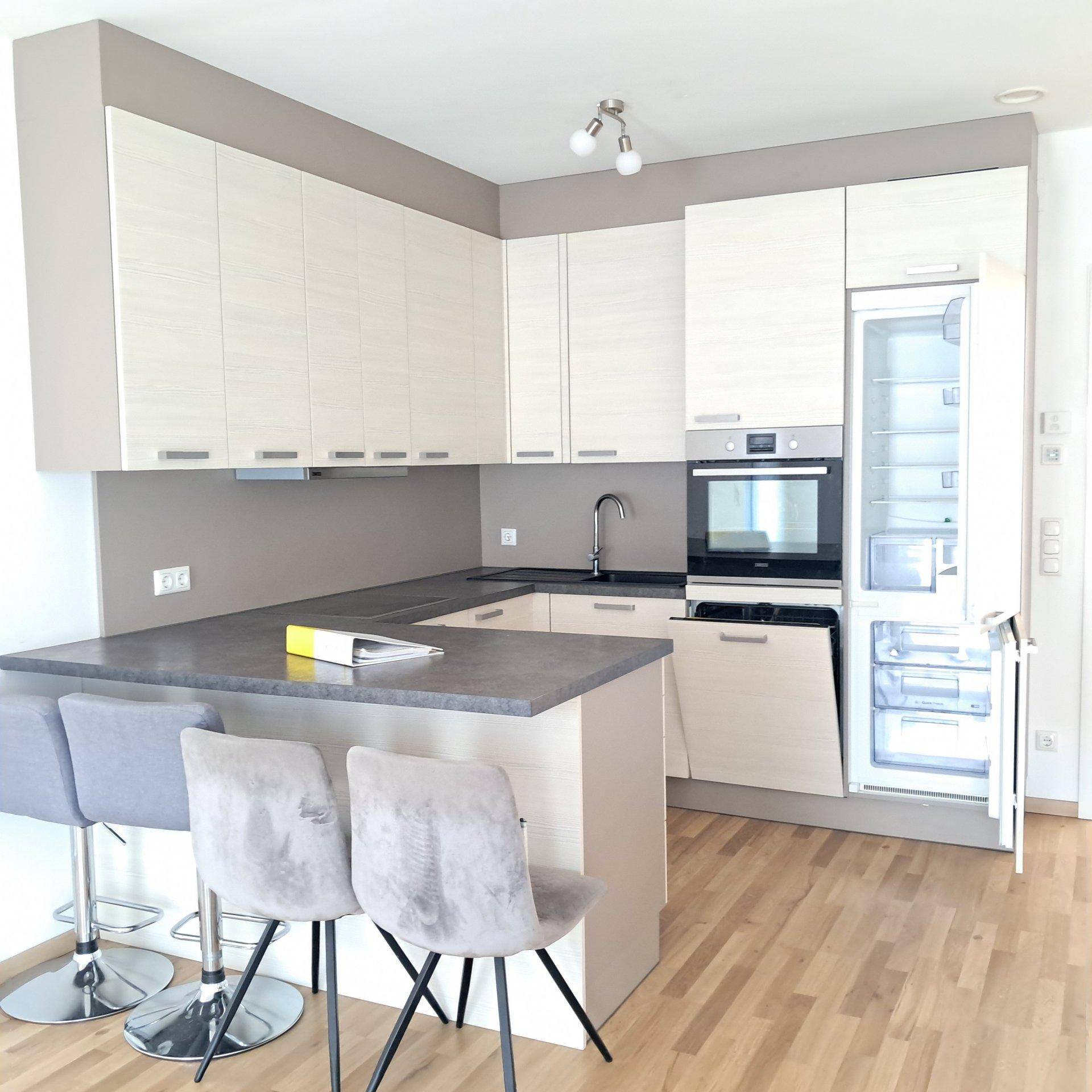 Helle Küche mit integrierten Geräten, Kühlschrank und stilvoller Frühstücksbar.