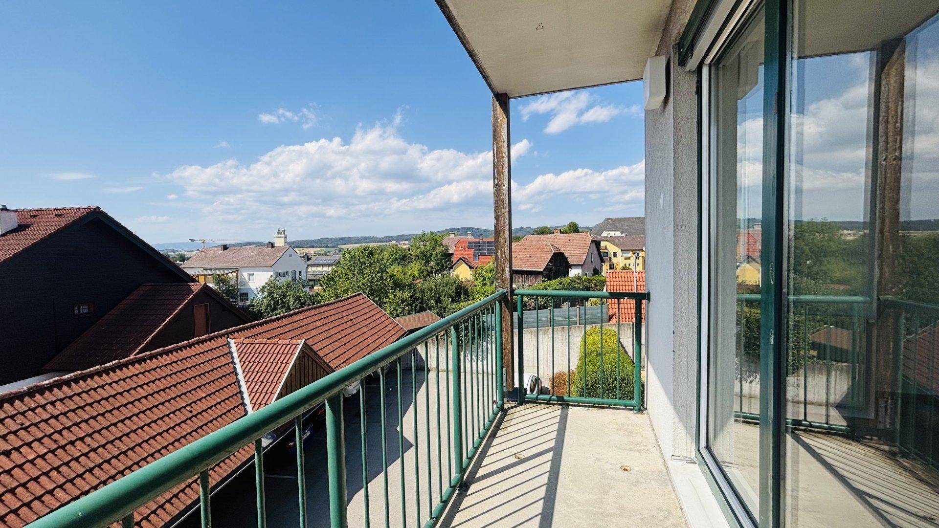 Geräumiger Balkon mit grüner Brüstung und weitem Blick über die Dächer und die Landschaft.