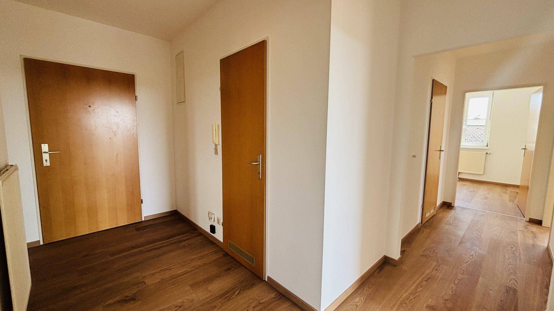 Heller Flur mit Holzfußboden und mehreren Türen, der zu verschiedenen Räumen führt.