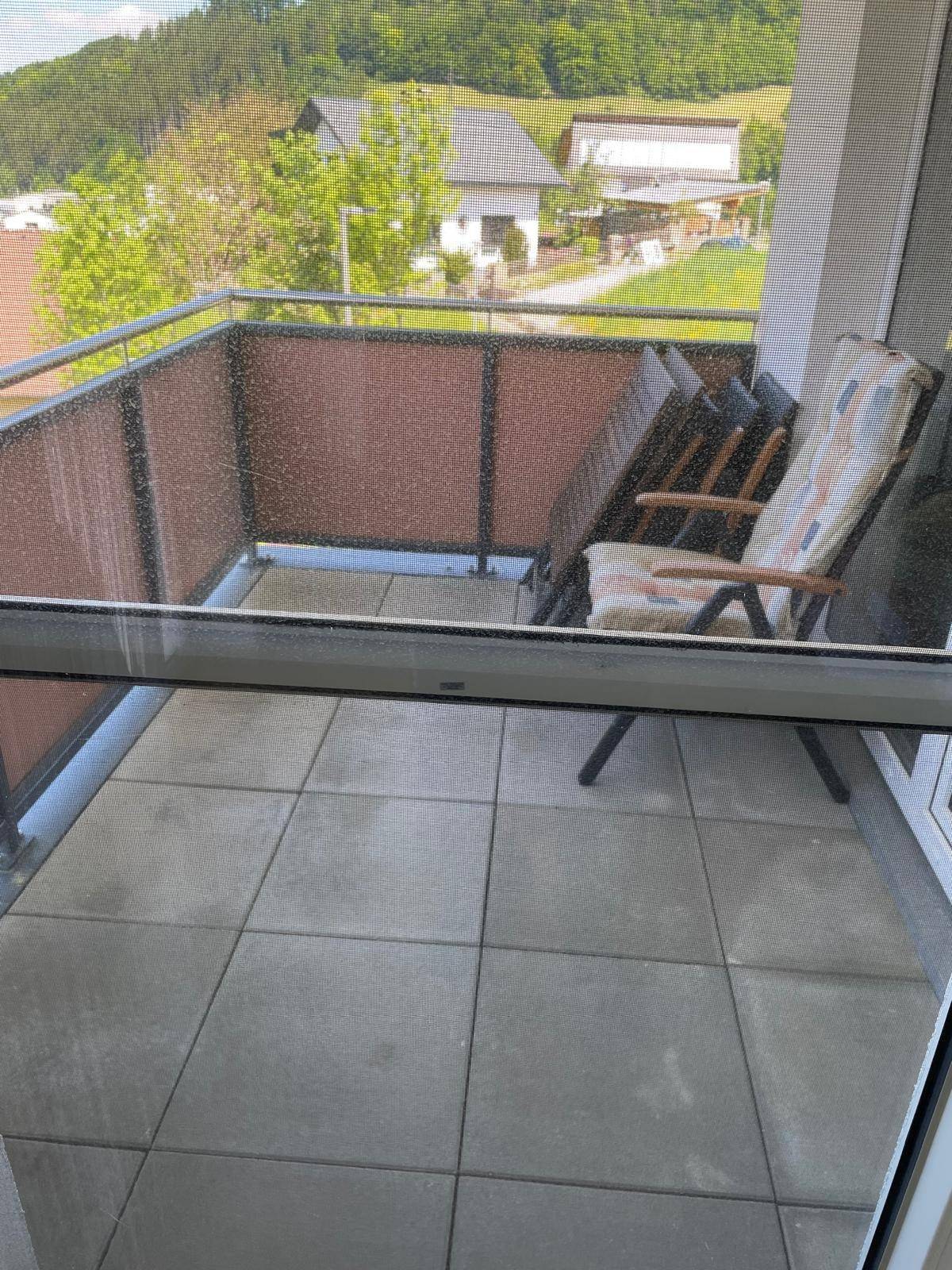 Geräumiger Balkon mit Fliesenboden, Sitzgelegenheiten und Blick ins Grüne.