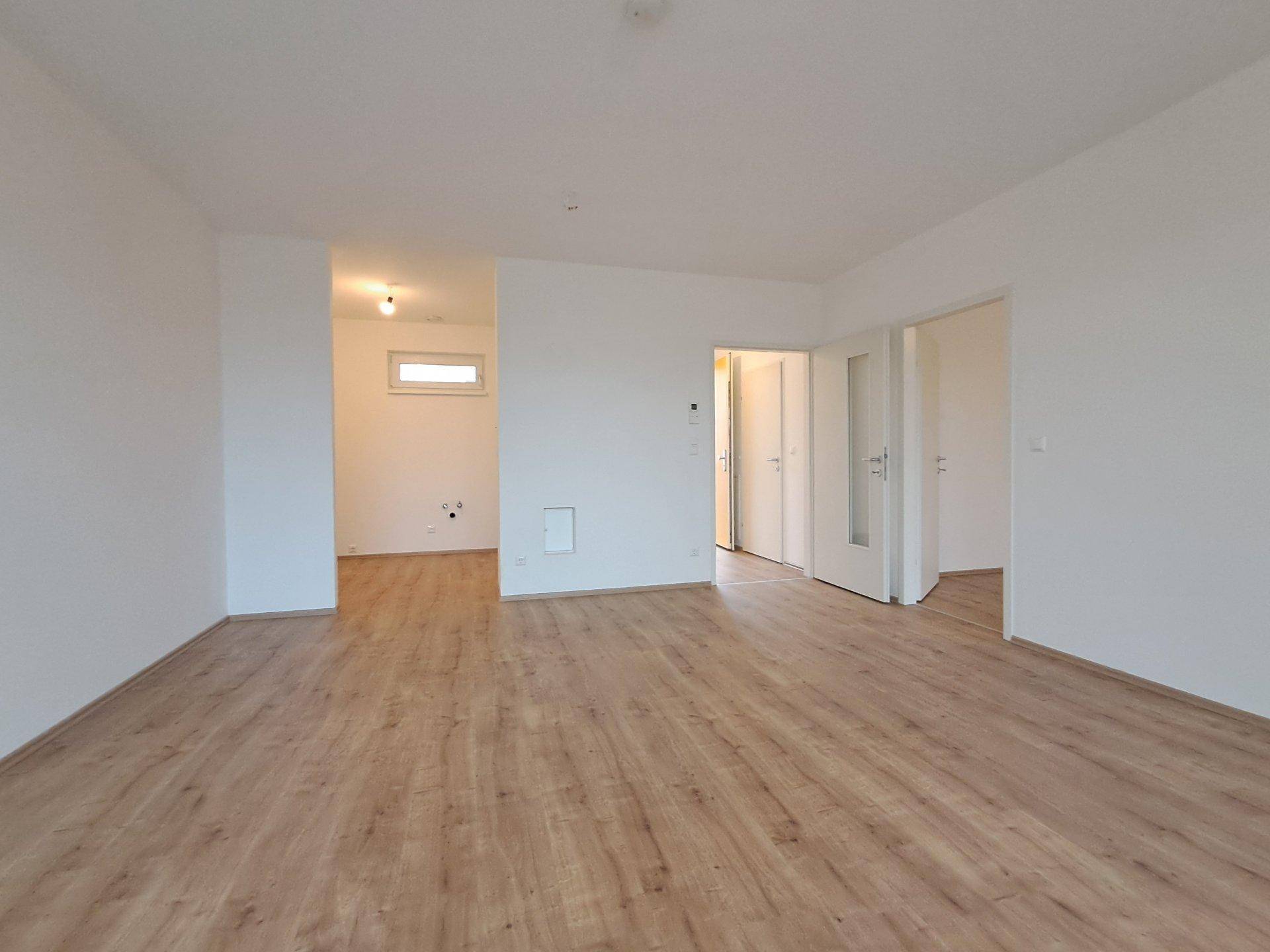 Heller, leerer Raum mit Laminatboden und weißen Wänden, bereit zum Einrichten.