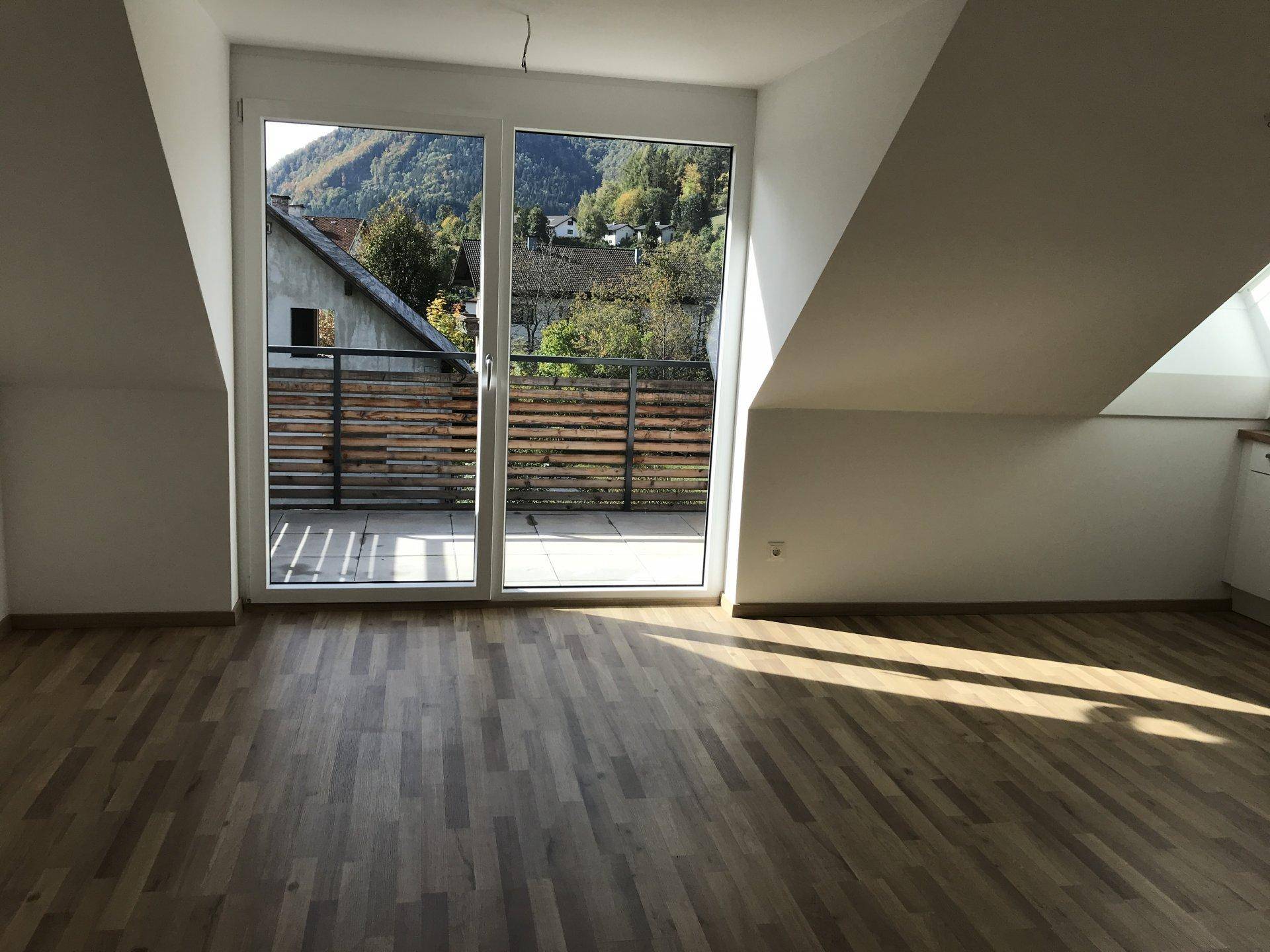 Lichtdurchfluteter Wohnbereich mit Holzfußboden und großem Zugang zu einem sonnigen Balkon.