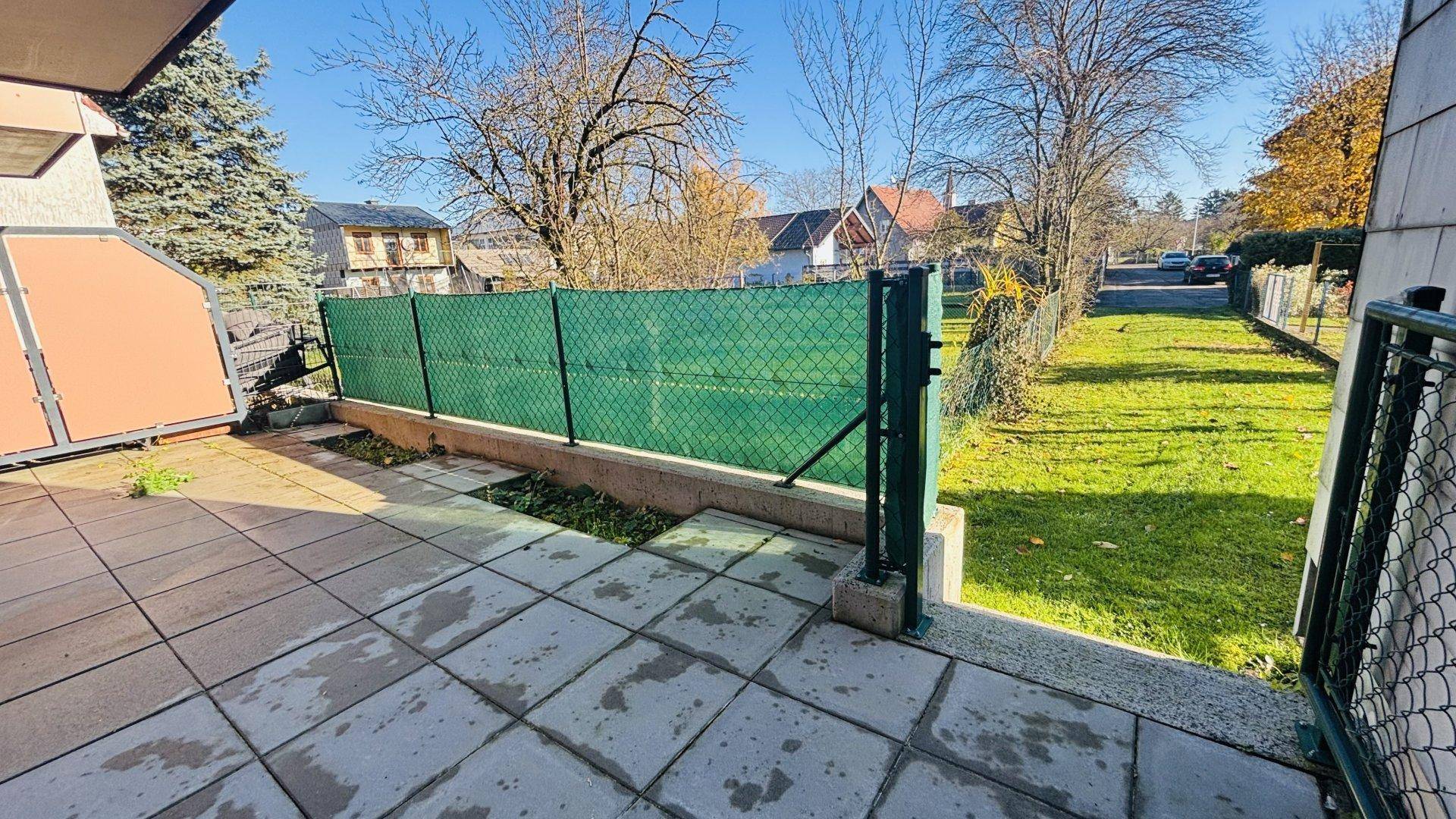 Geräumige Terrasse mit Steinplatten und Blick auf die grüne Umgebung.