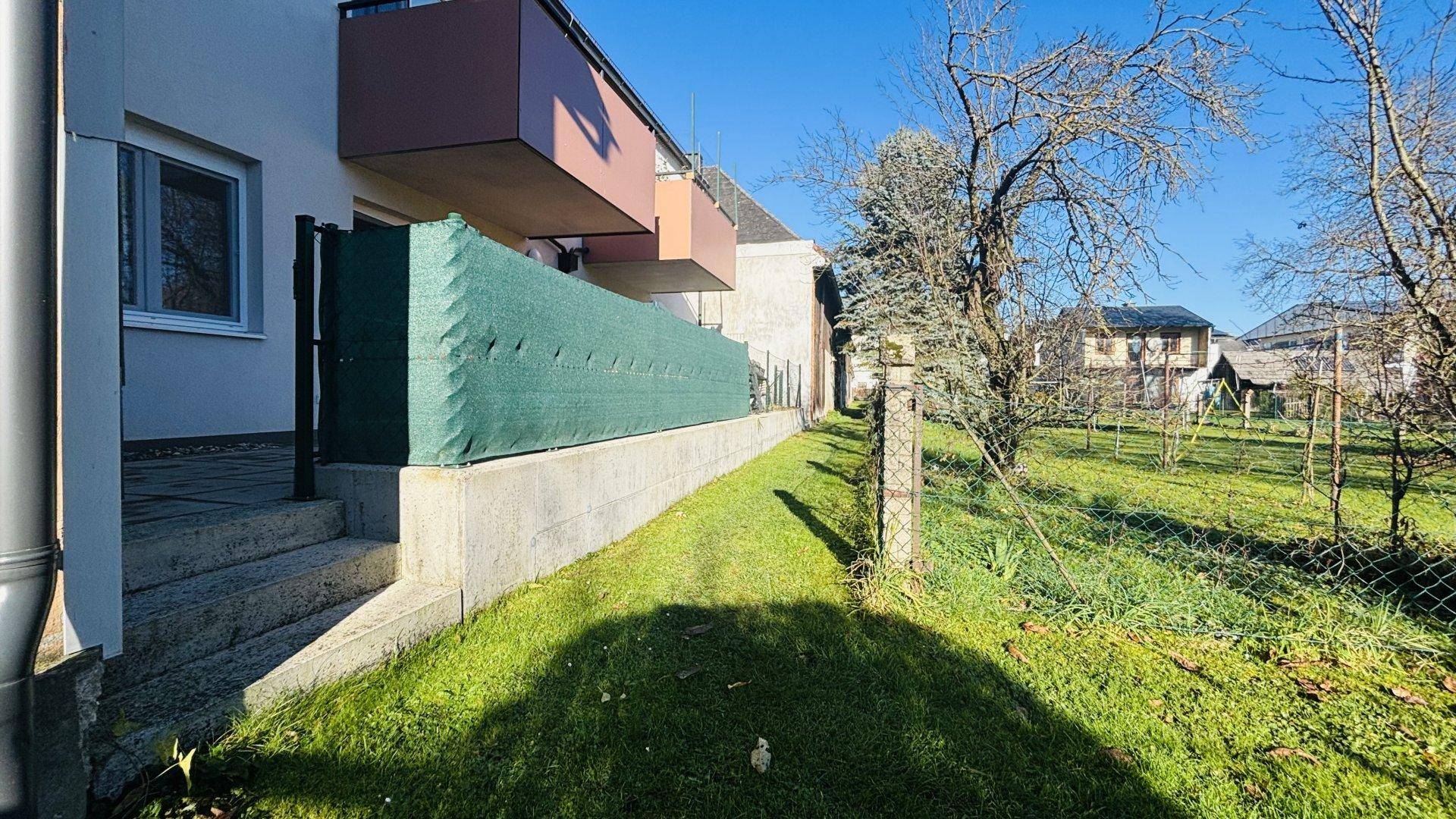 Grüner Gartenbereich mit Rasenfläche und Treppe zur oberen Terrasse.