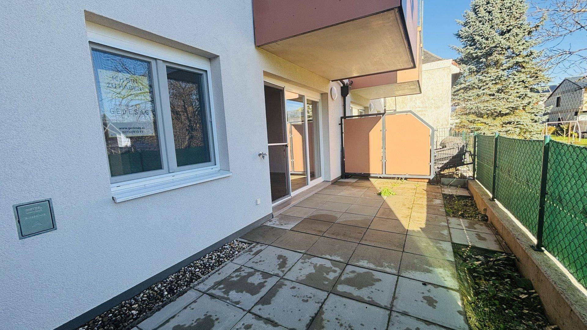 Helle Terrasse mit Fliesenboden und Zugang zum Innenbereich des Hauses.