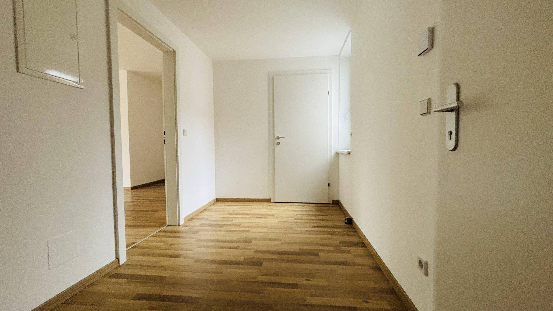 Heller Flur mit Parkettboden, der zu verschiedenen Räumen der Wohnung führt.