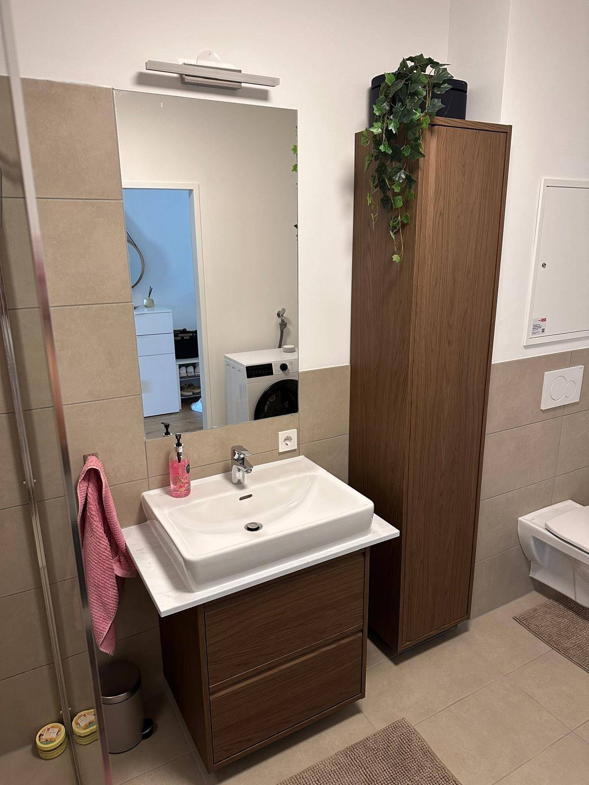 Modernes Badezimmer mit Waschtischunterschrank, großem Spiegel und Wand-WC.