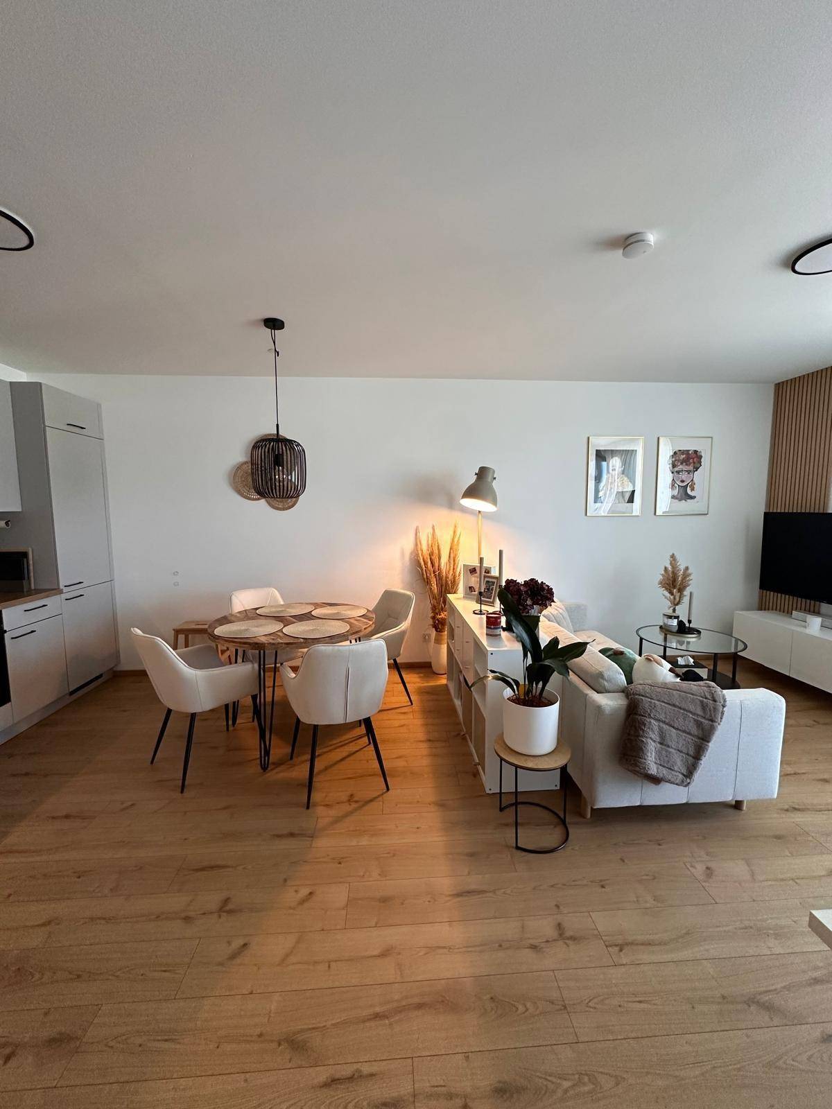 Heller Wohn-Essbereich mit Esstisch, Sofa und modernem Dekor, ideal für gesellige Stunden.
