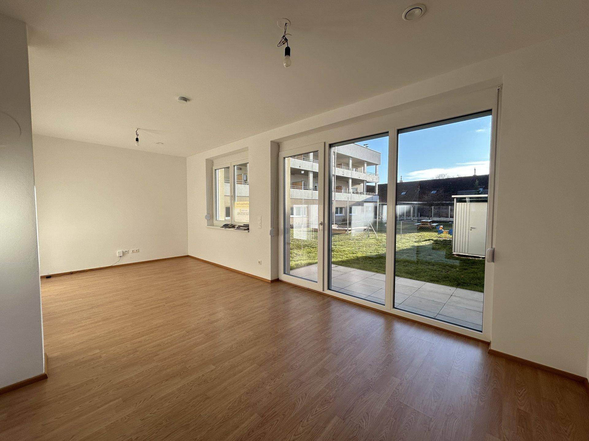 Helles Wohnzimmer mit Laminatboden und Zugang zu einer Terrasse und dem Gartenbereich.