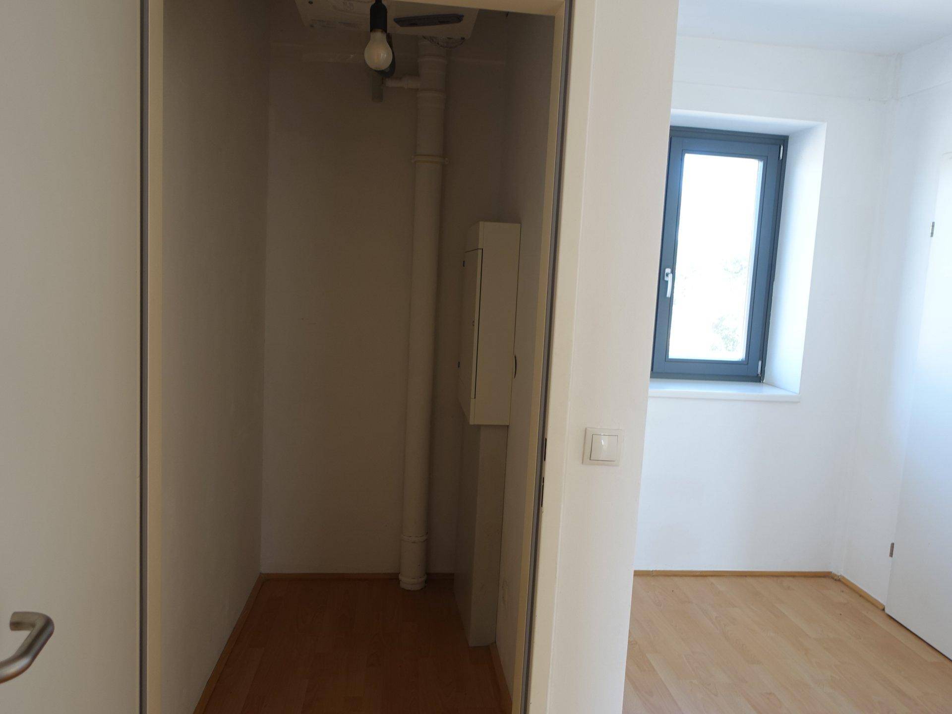 Kleiner Abstellraum mit Fenster und einfacher Beleuchtung.