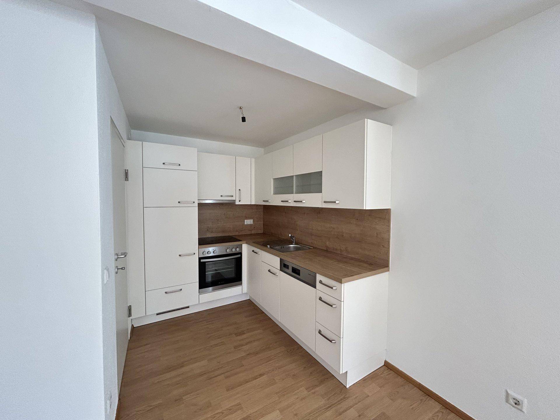 Moderne Einbauküche mit weißen Schränken, Holz-Arbeitsplatte und integrierten Geräten.
