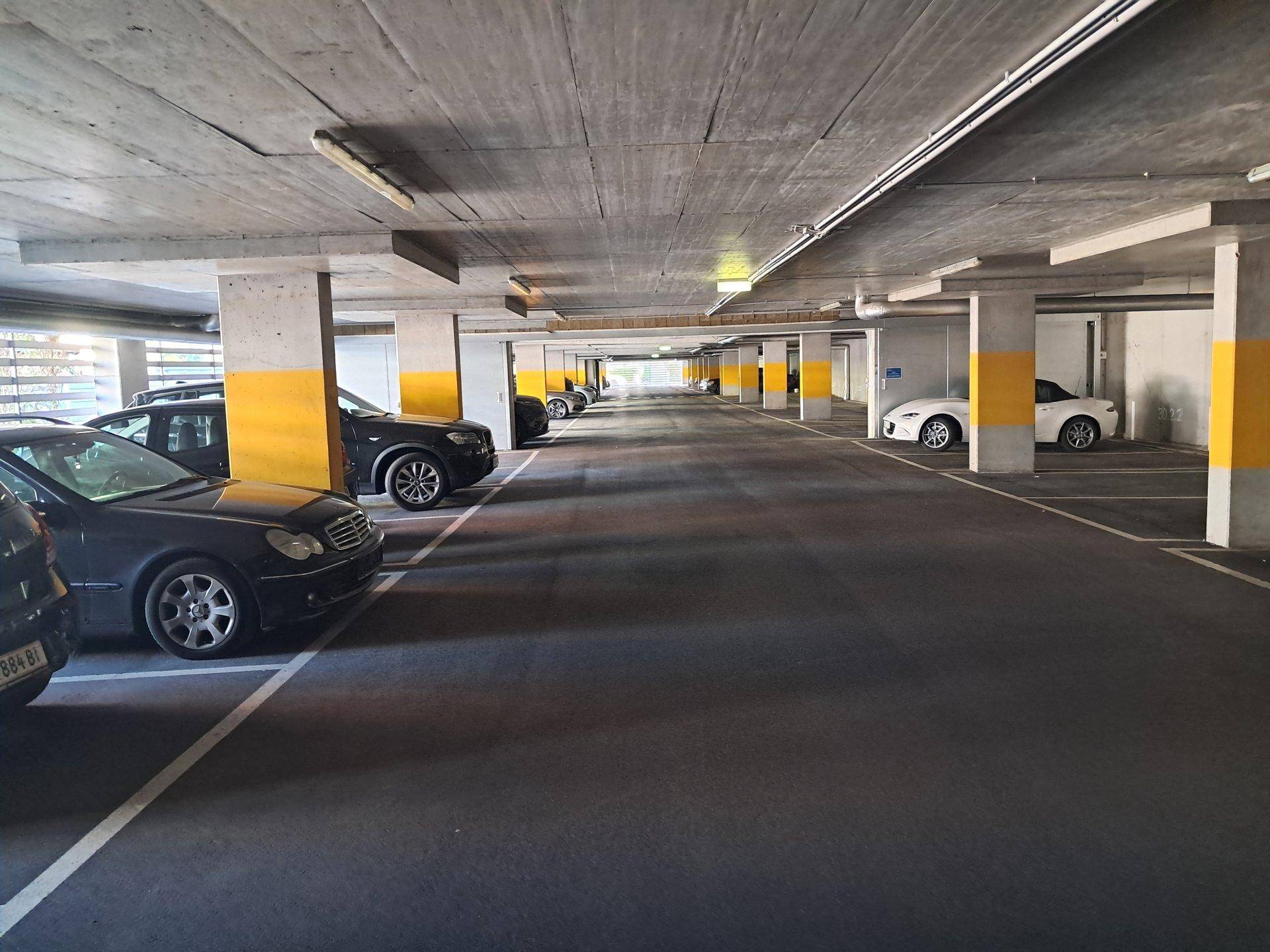 Geräumige Tiefgarage mit vielen Parkplätzen und gelb markierten Säulen.