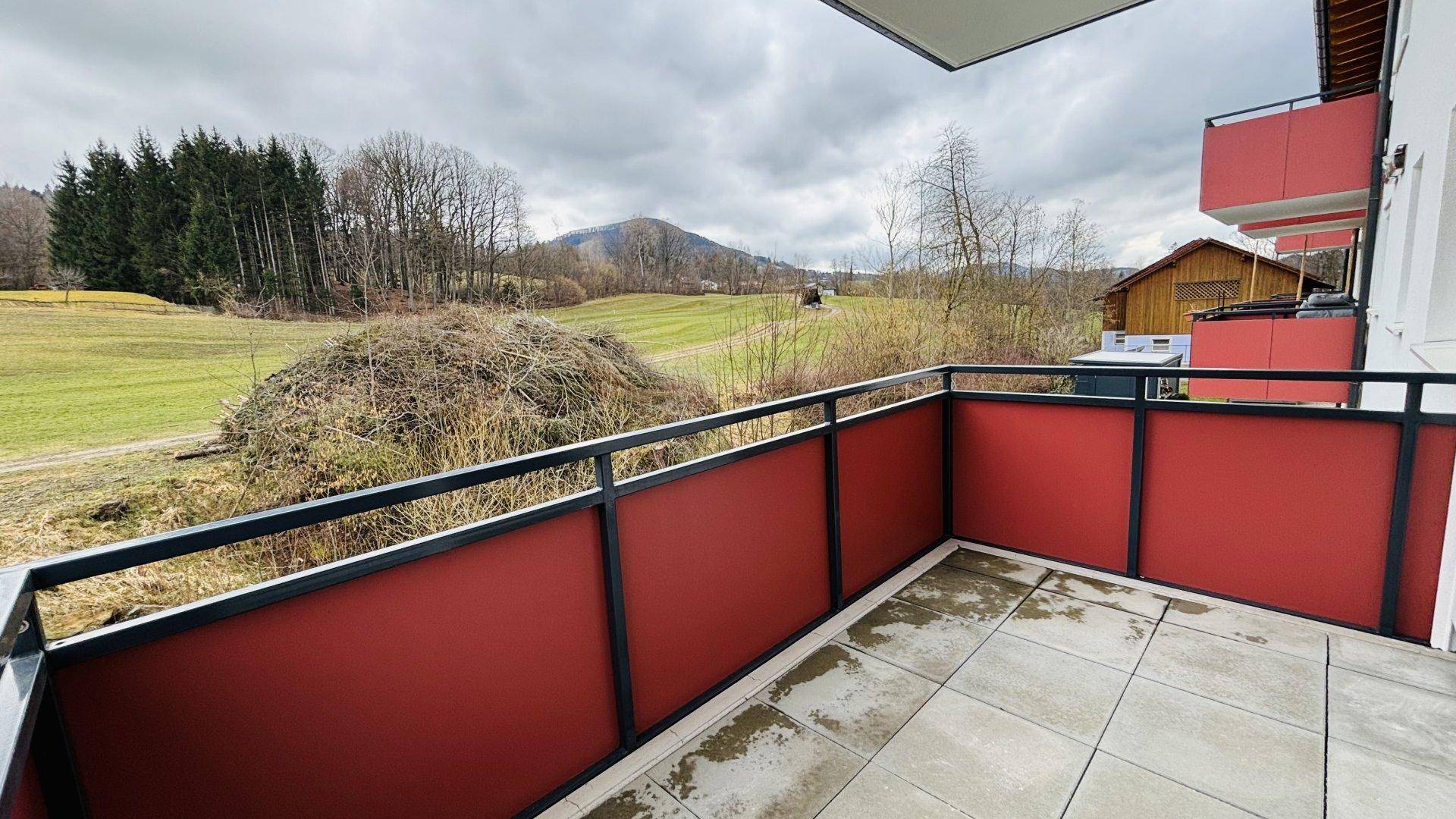 Balkon mit Panoramablick auf die grüne Hügellandschaft und den bewaldeten Berg.