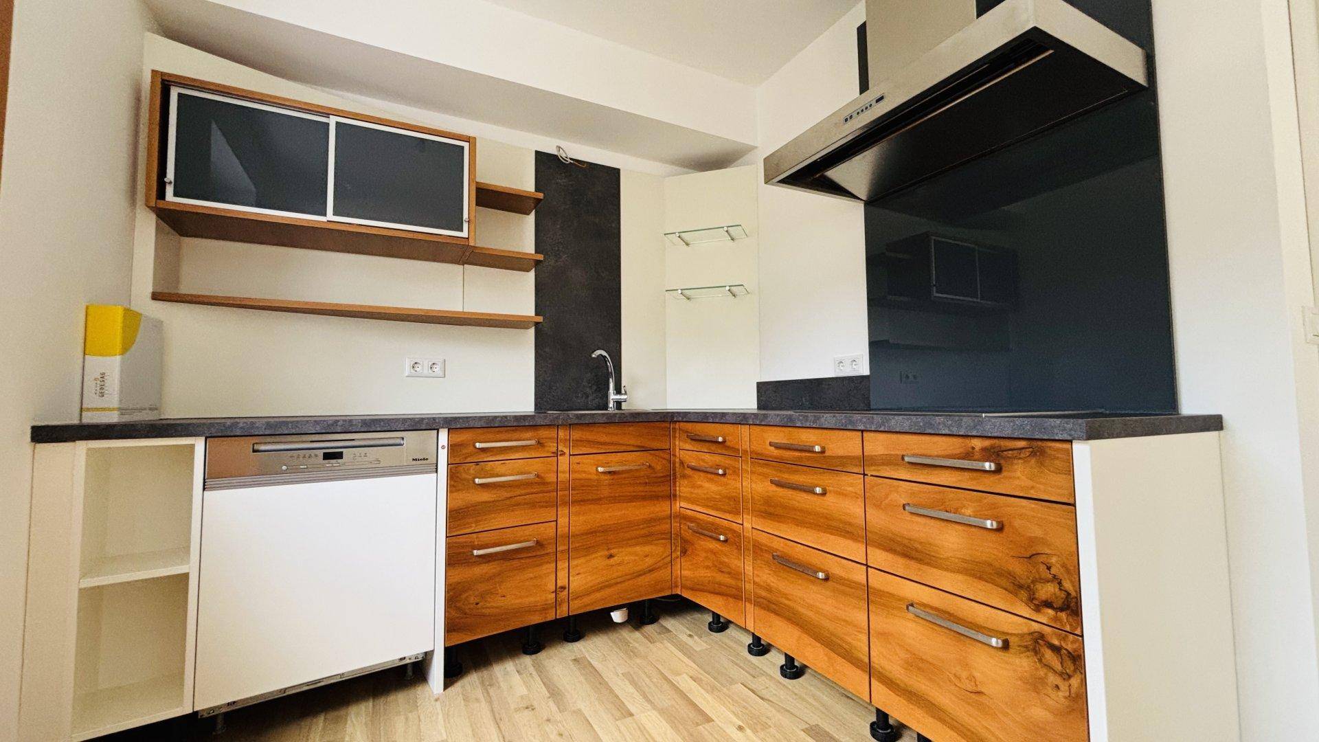Moderne Einbauküche mit Holzelementen, dunkler Arbeitsplatte und integriertem Geschirrspüler.