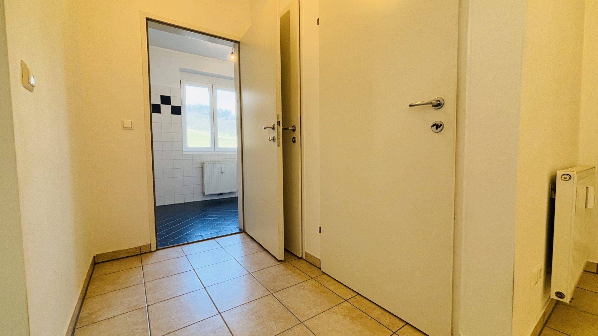 Heller Flur mit Fliesenboden und Zugang zu verschiedenen Räumen, inklusive Badezimmer.