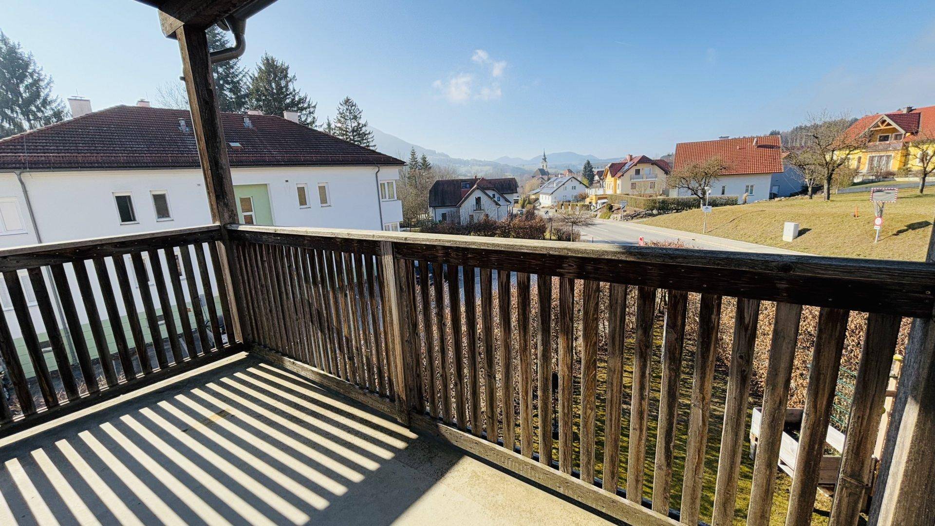 Geräumiger Holzbalkon mit Blick auf die umliegende Landschaft und die Berge.