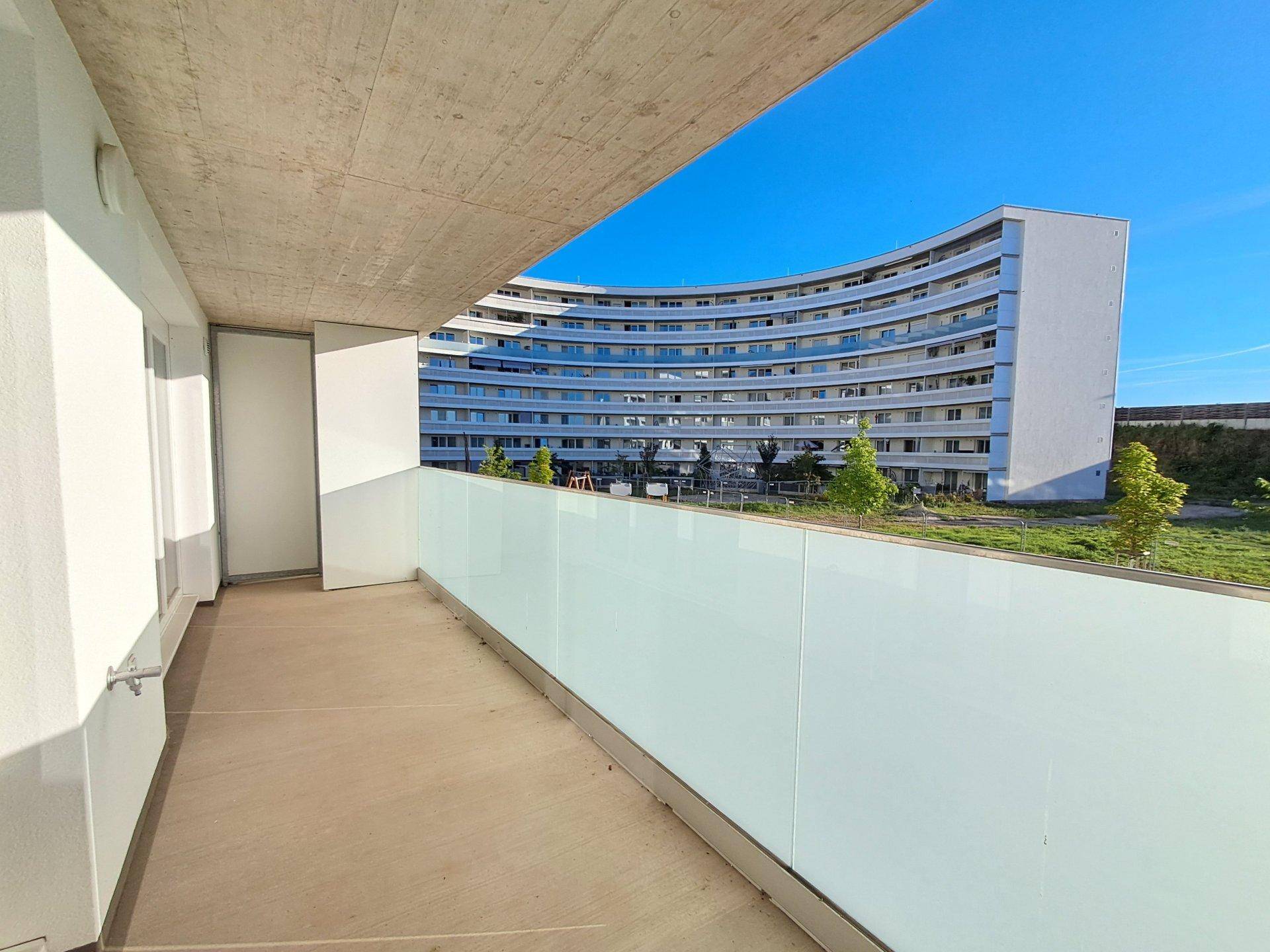 Balkon mit Glasbrüstung und Blick auf die umliegende moderne Wohnbebauung.