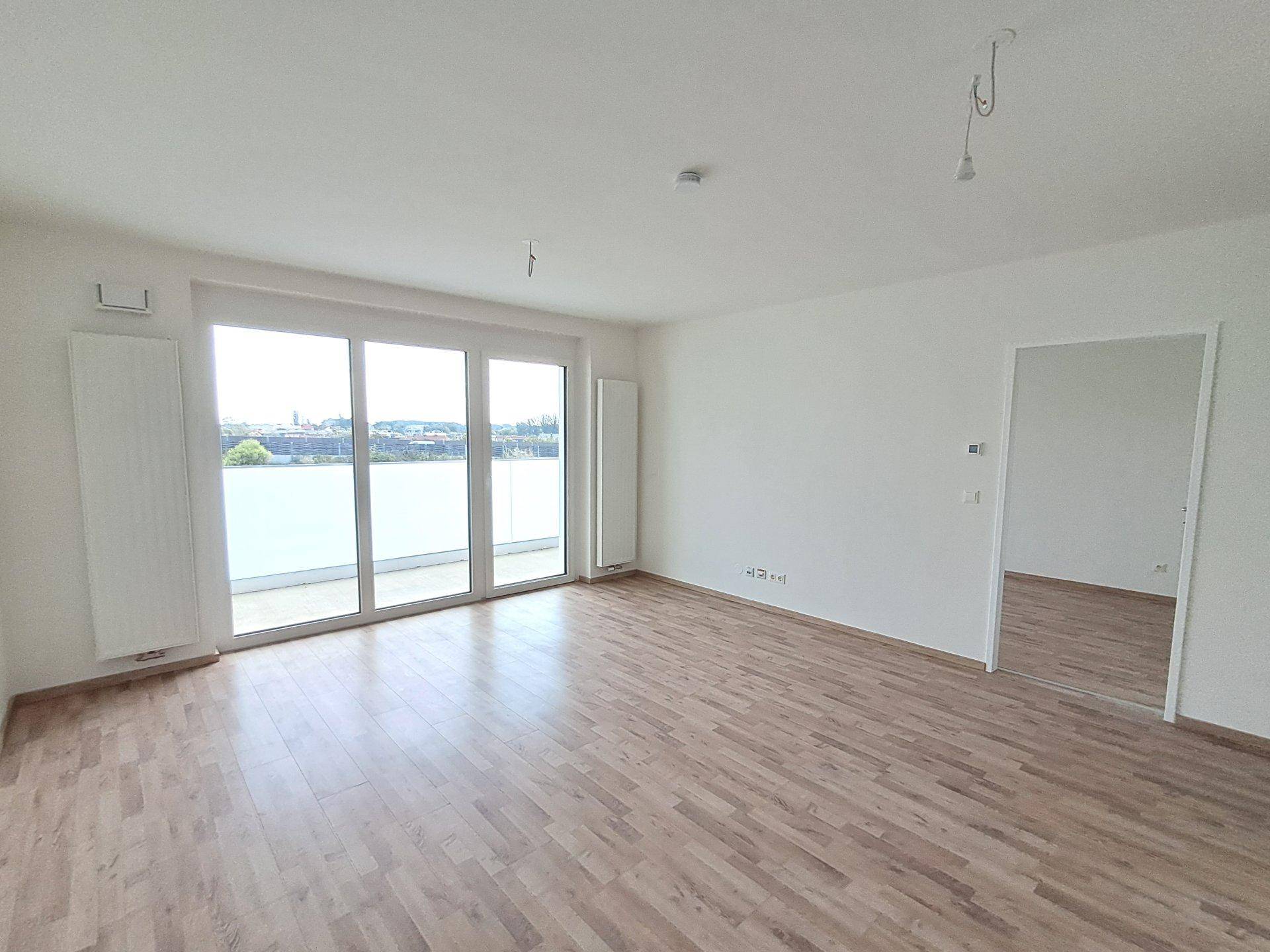 Lichtdurchflutetes Wohnzimmer mit Holzfußboden und direktem Zugang zum Außenbereich.