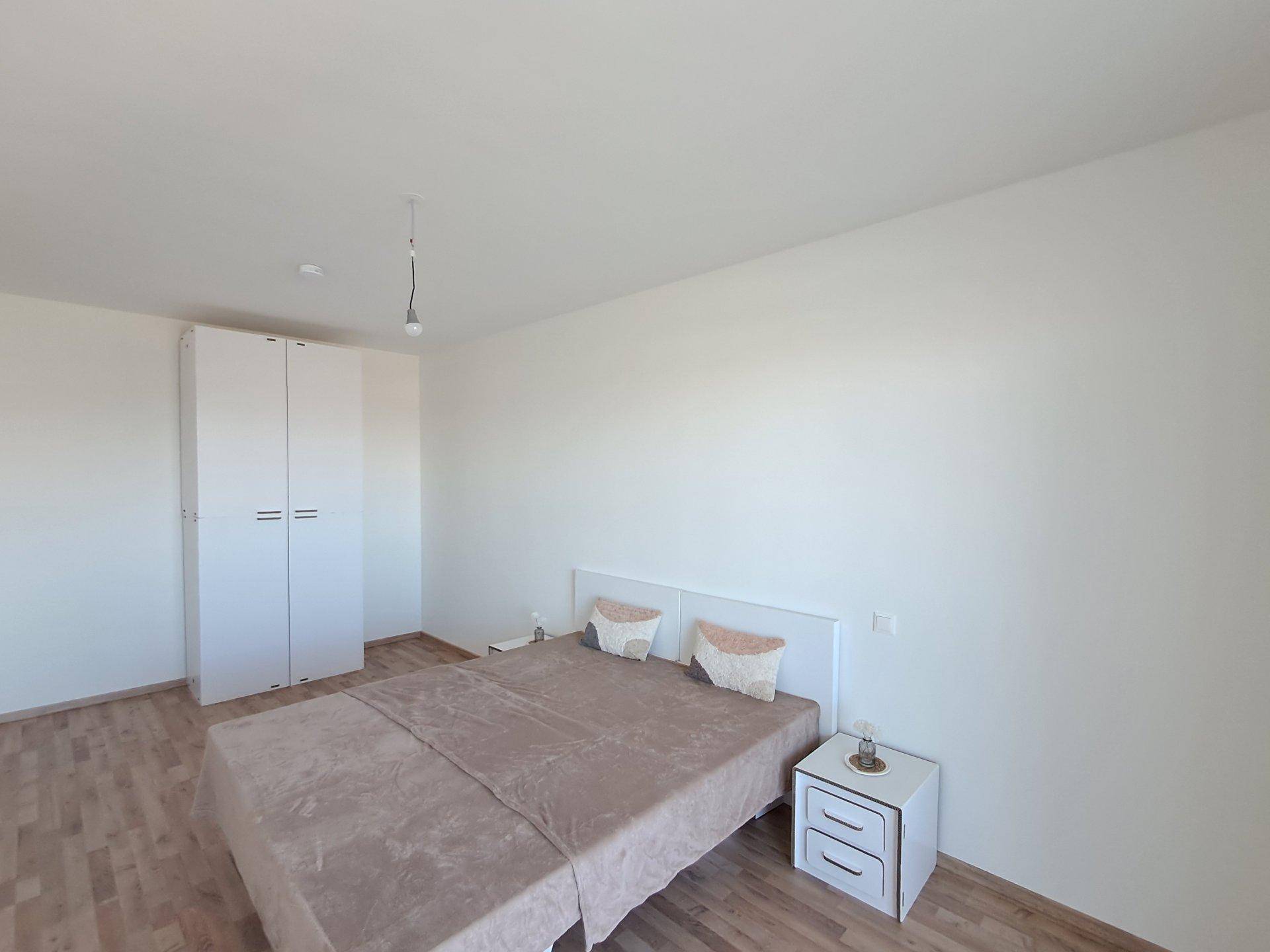 Helles Schlafzimmer mit Laminatboden, weißem Kleiderschrank und Nachttischen.