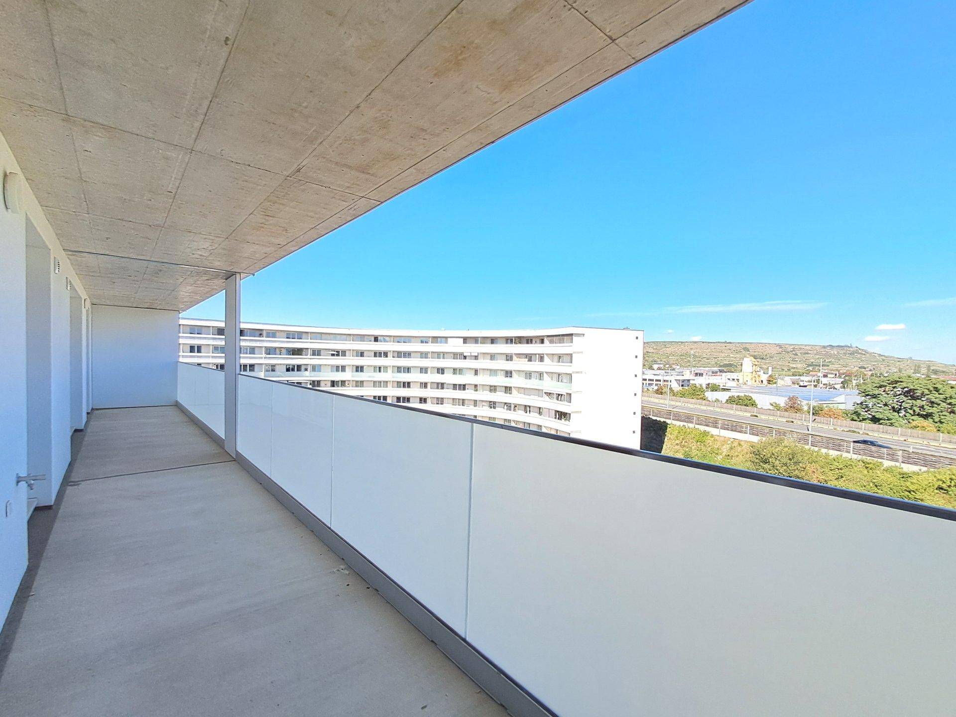 Geräumiger Balkon mit moderner Glasbrüstung und Panoramablick auf die umliegende Landschaft.