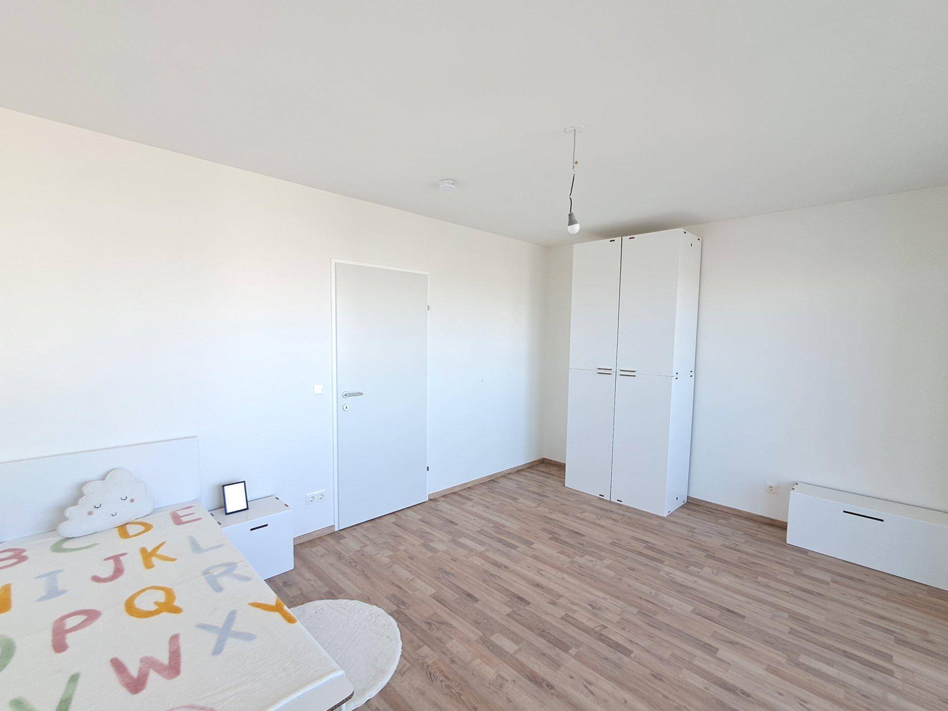 Helles Kinderzimmer mit Laminatboden und weißem Kleiderschrank, bereit zur individuellen Gestaltung.