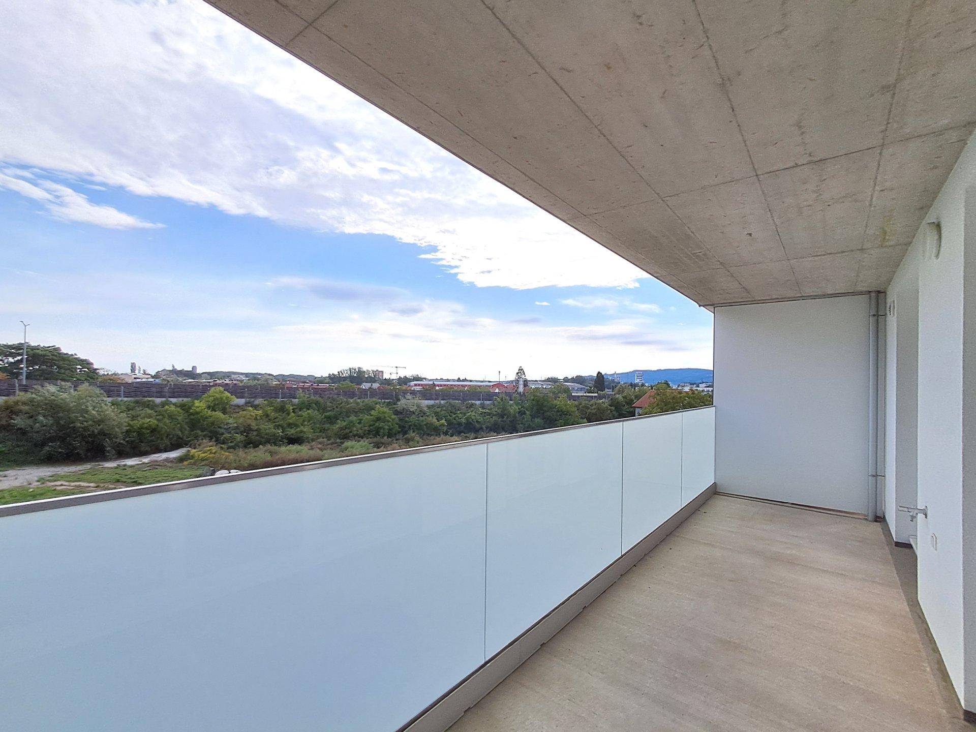 Heller Balkon mit weitem Blick ins Grüne und auf die Stadt am Horizont.