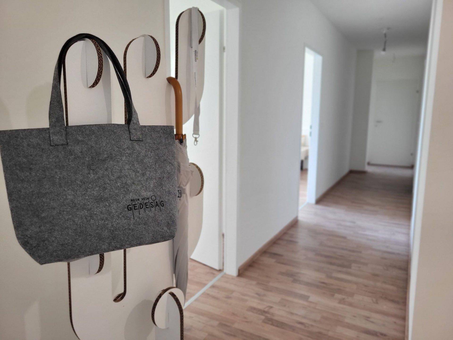 Heller Flur mit Holzfußboden und Garderobe, der zu weiteren Räumen führt.