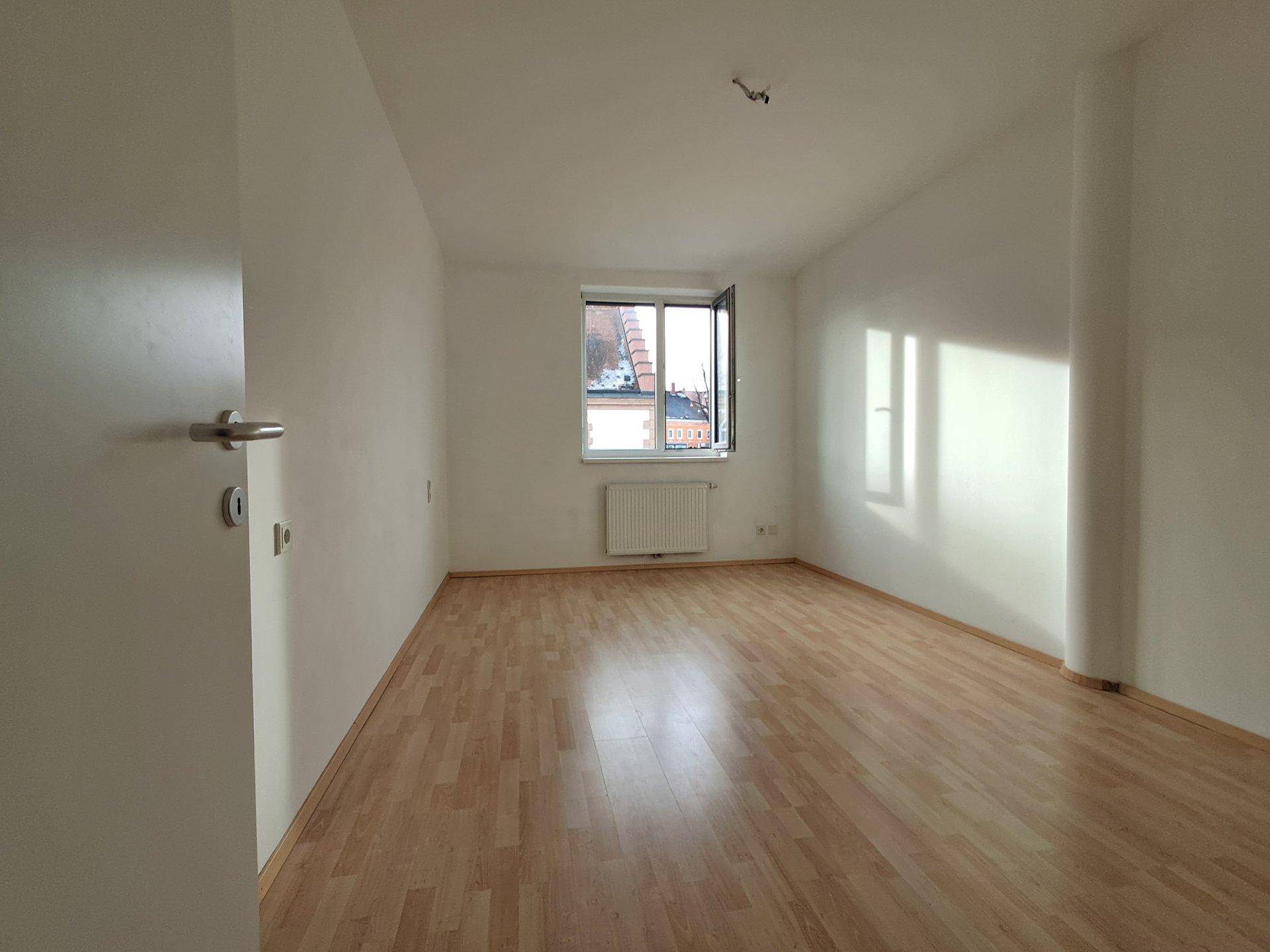 Geräumiges, helles Zimmer mit Laminatboden und weißen Wänden, ideal als Schlaf- oder Arbeitszimmer.