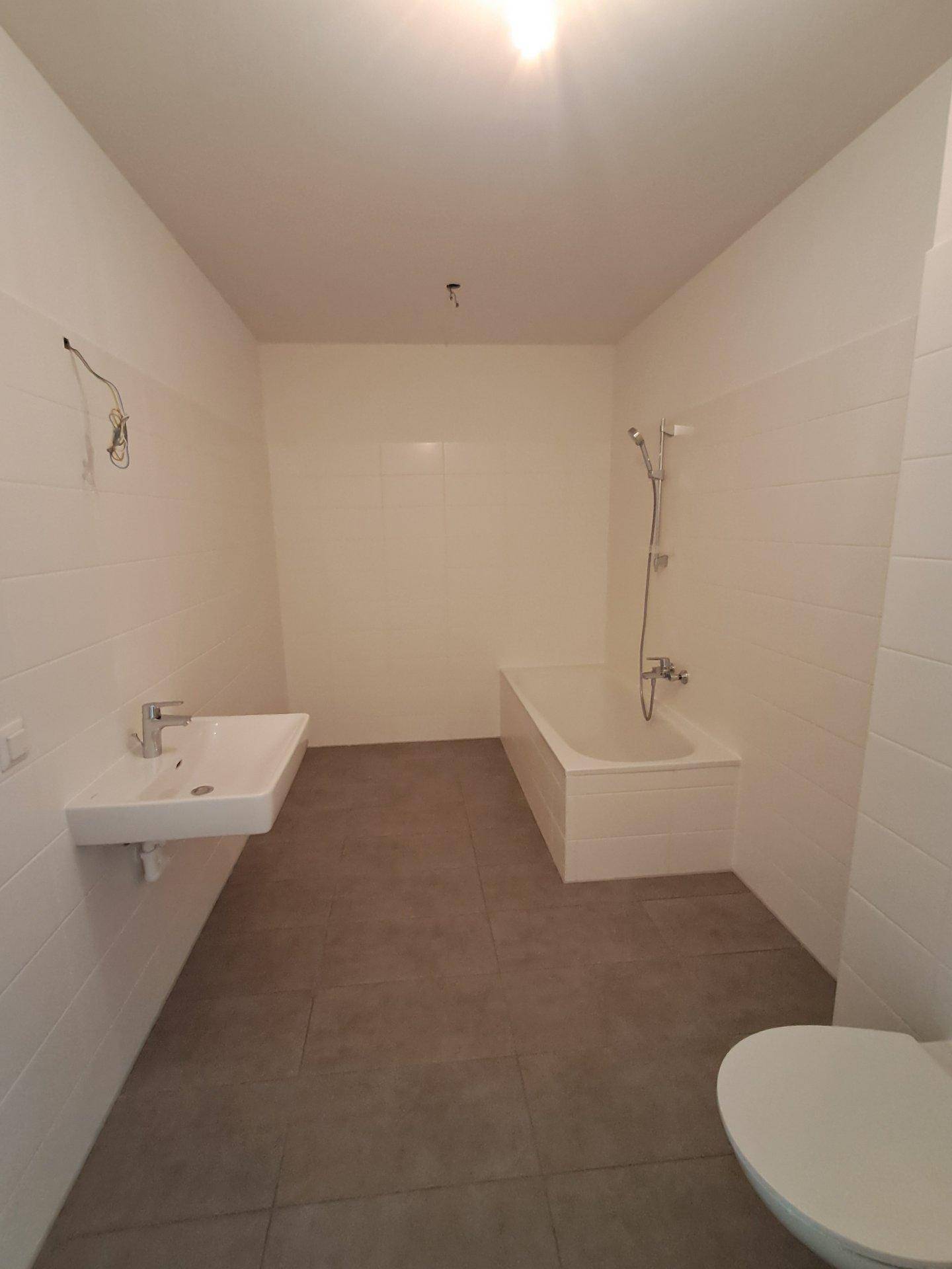 Modernes Badezimmer mit Badewanne, Waschbecken und Toilette, hell gefliest.