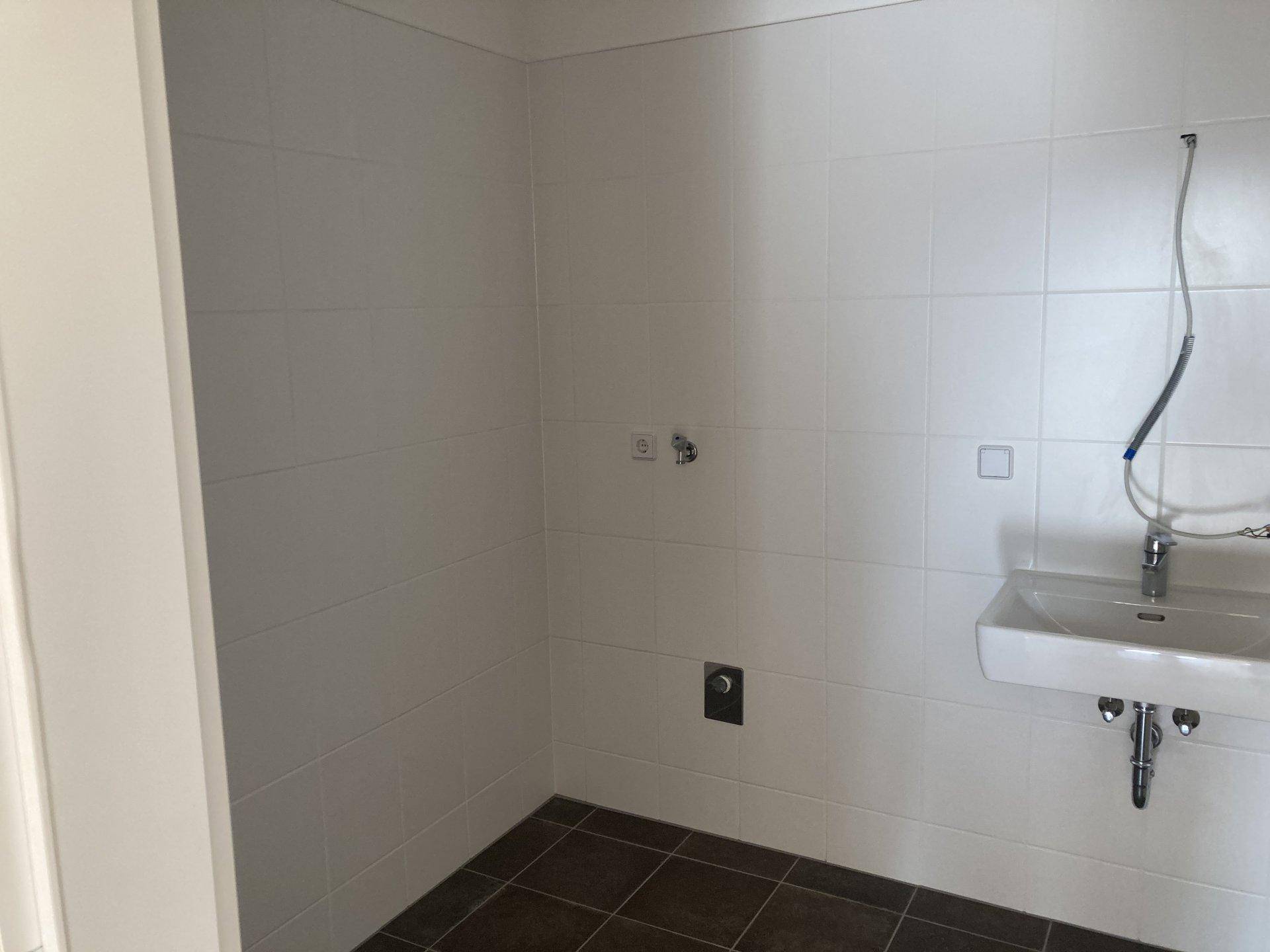 Modernes Badezimmer mit weißen Fliesen, dunklem Boden und einem Waschbecken.