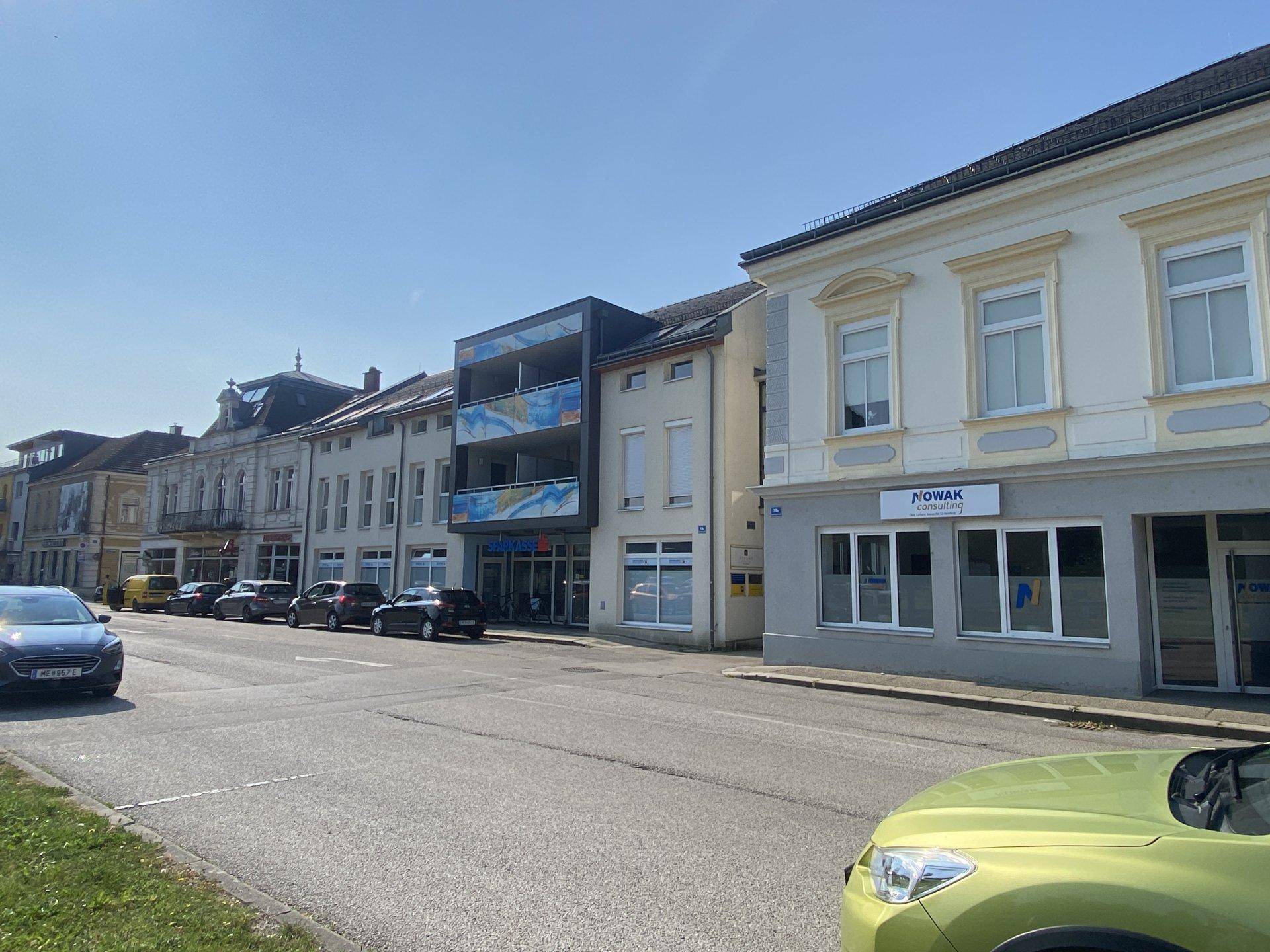 Belebtes Straßenbild mit einer Mischung aus historischen und modernen Gebäuden unter blauem Himmel.