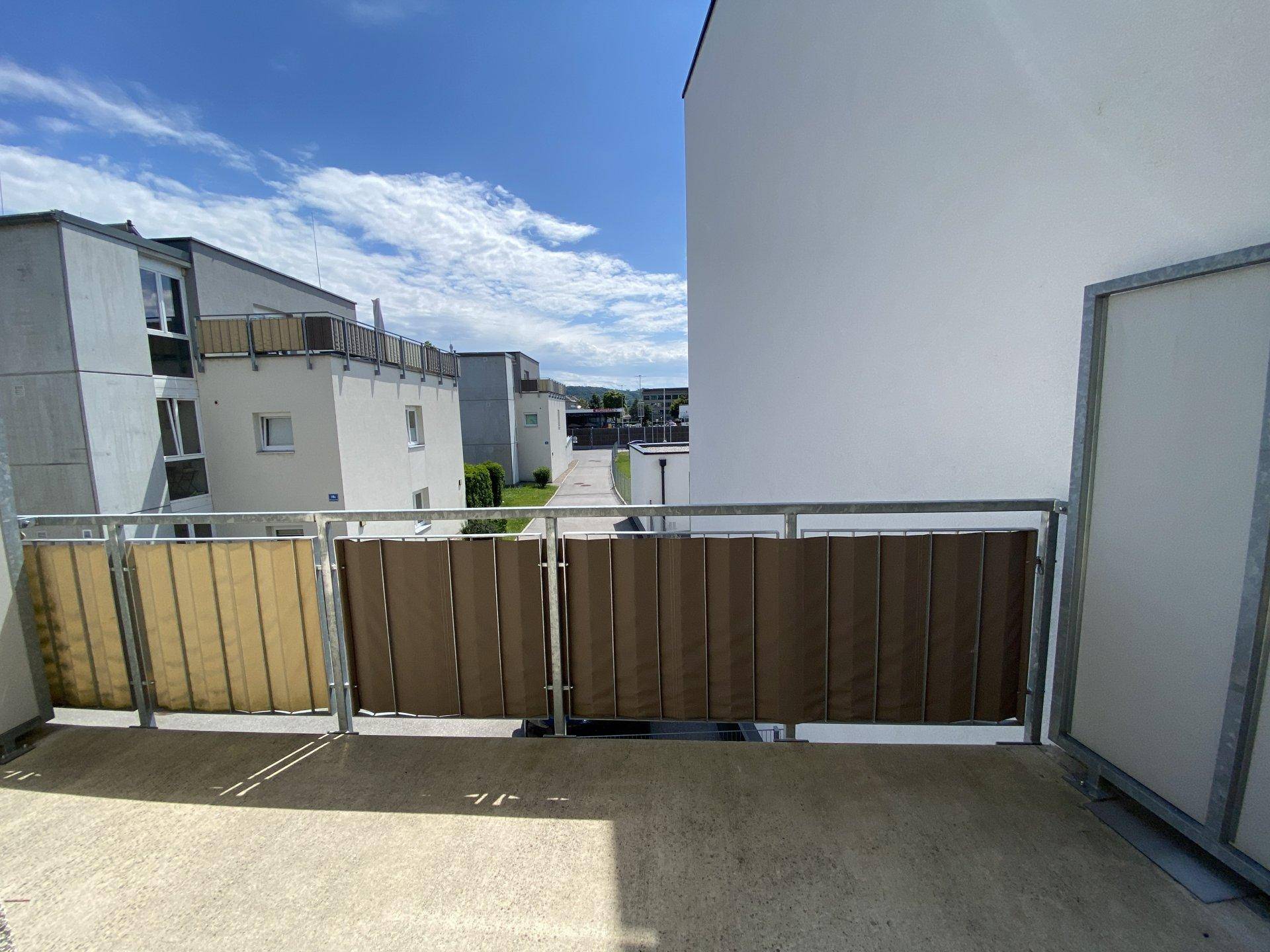 Heller Balkon mit Sichtschutz und Blick auf die umliegenden Wohngebäude.