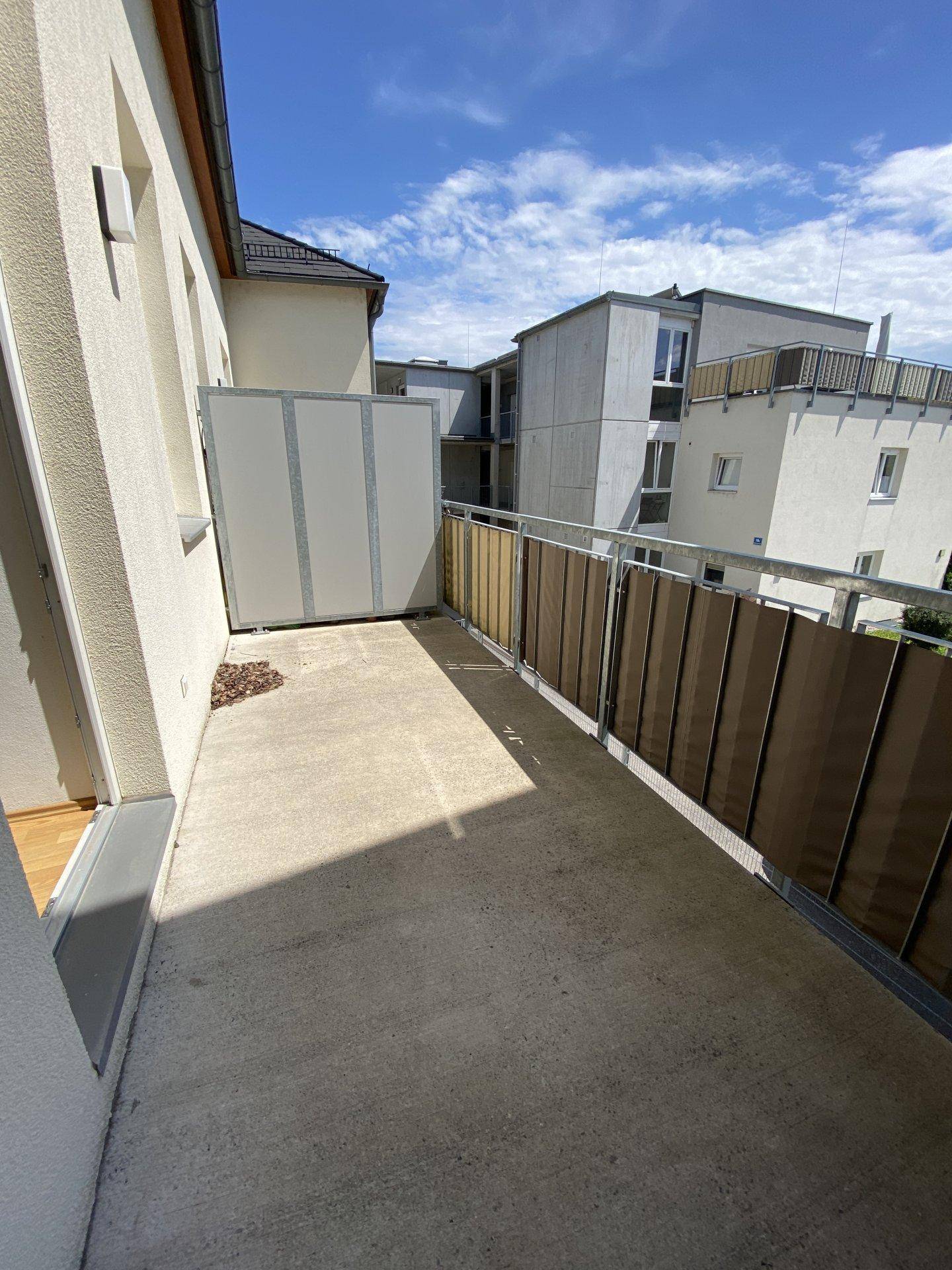 Geräumiger Balkon mit braunem Sichtschutz und Blick auf die benachbarten Gebäude.