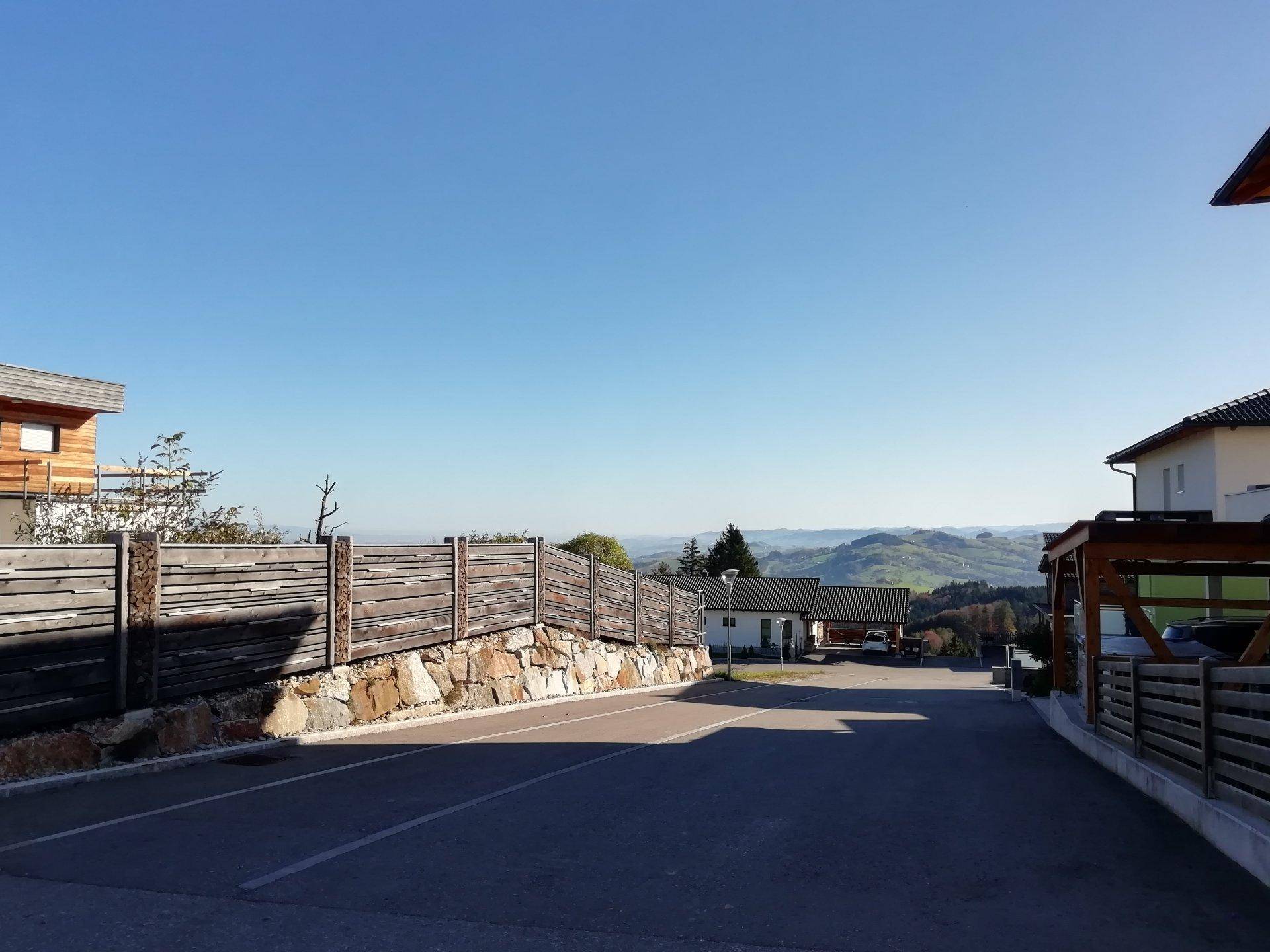 Zufahrt zum Anwesen mit Holzzaun und weitem Blick auf die hügelige Landschaft.